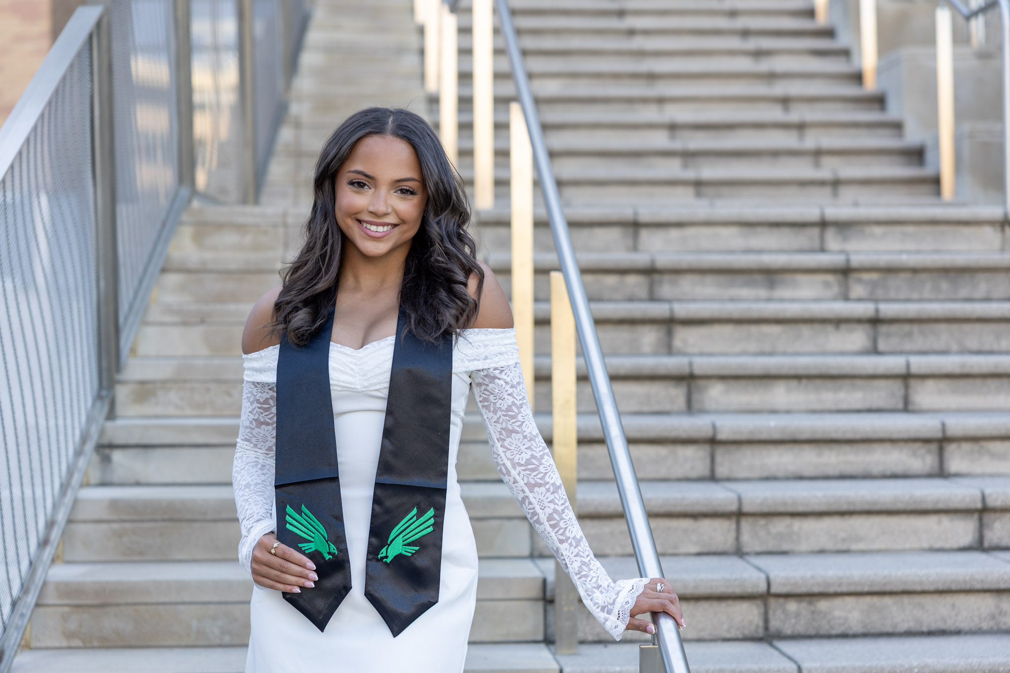 Skylar Allen wearing a UNT stole on outdoor campus stairs in Denton