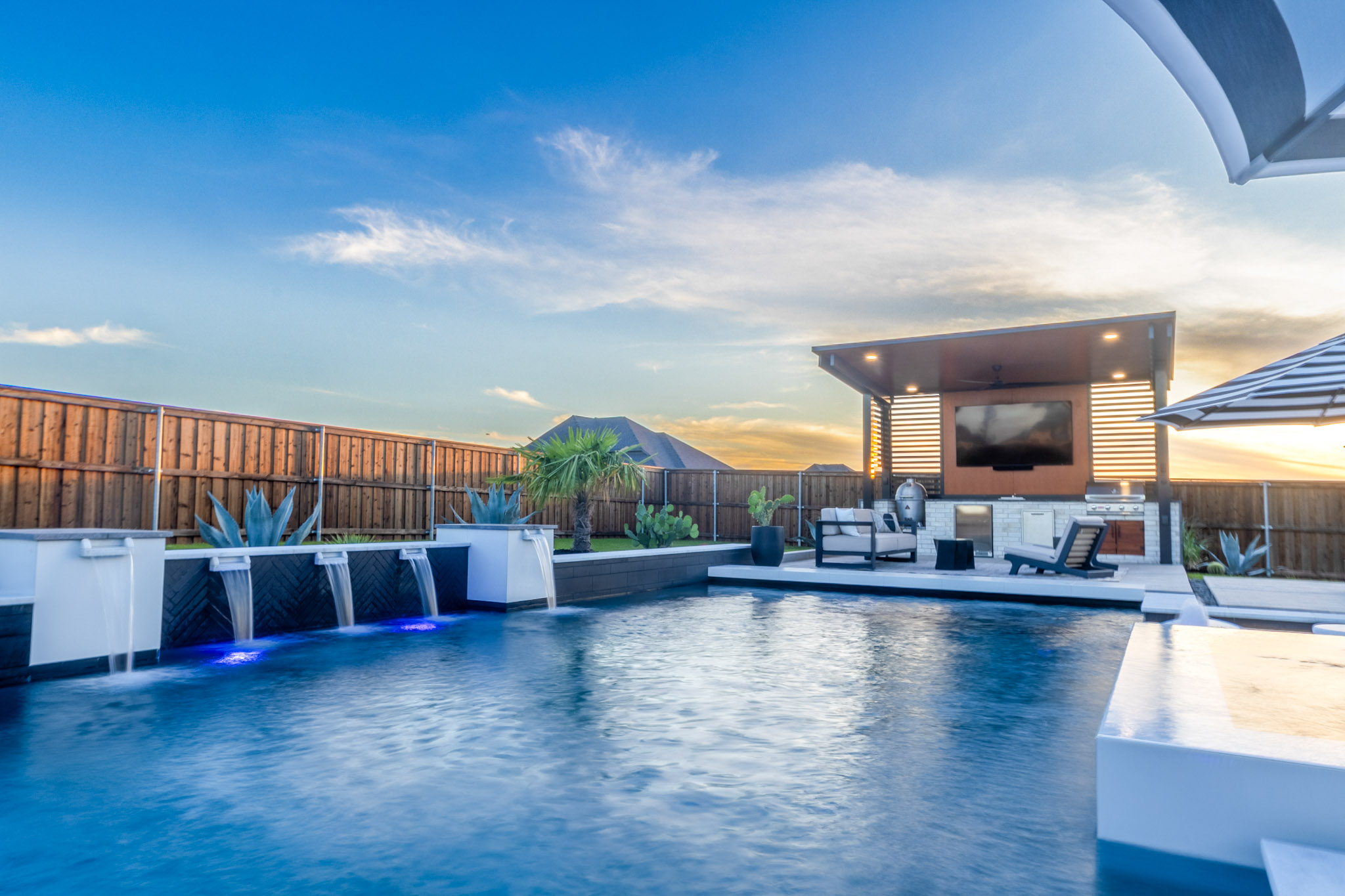 Luxury backyard pool with water features and outdoor kitchen pavilion in Rockwall, Texas.