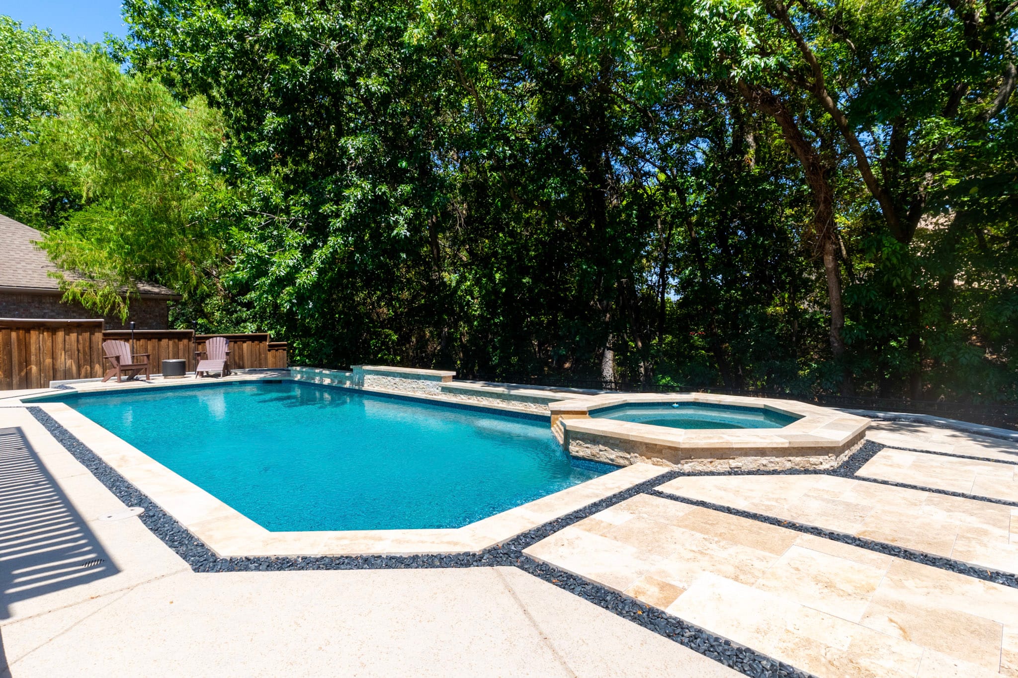 Geometric swimming pool with raised spa, tiered spillover and light stone decking in McKinney.