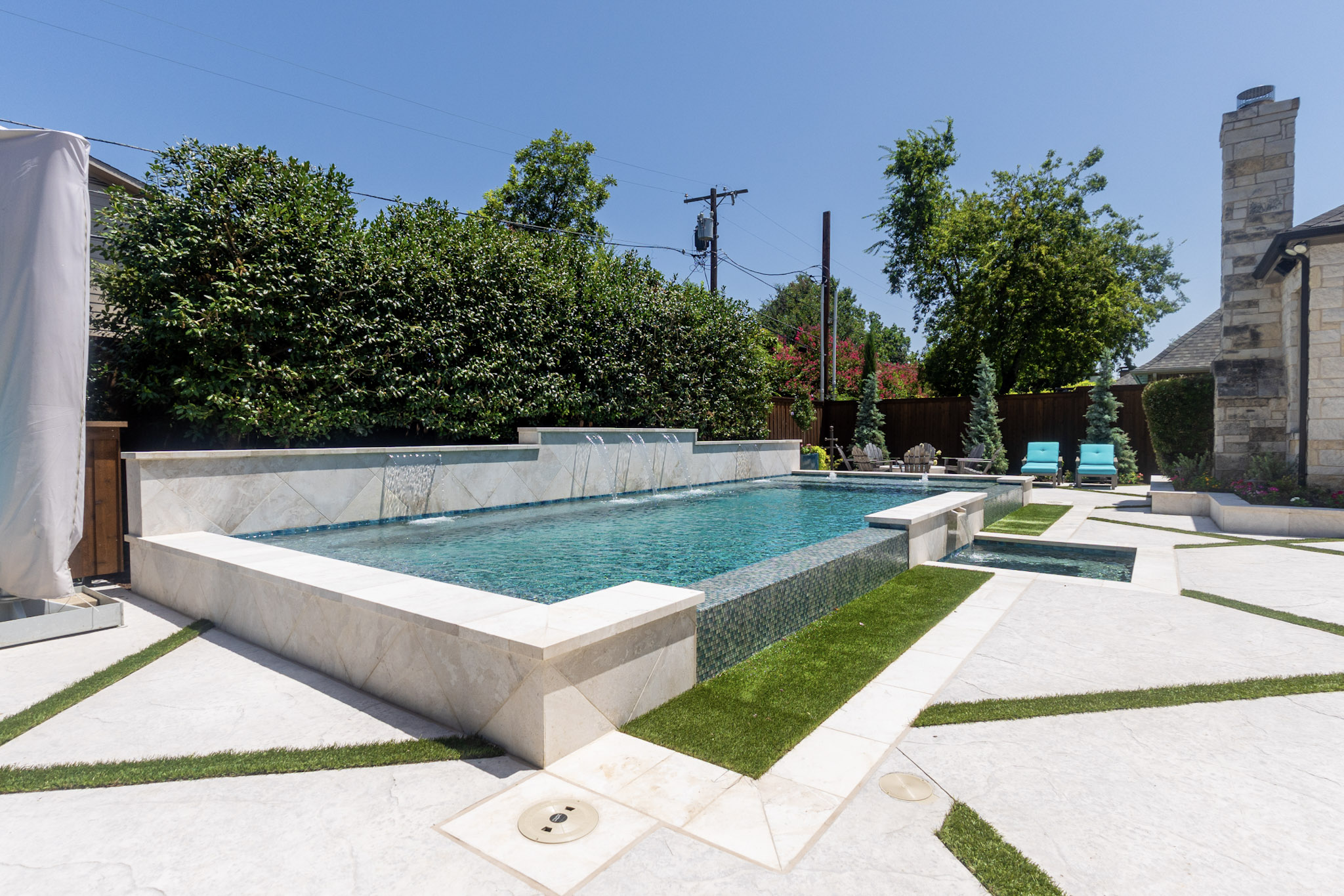 Custom vanishing edge pool and spa with raised water feature wall in University Park, Texas