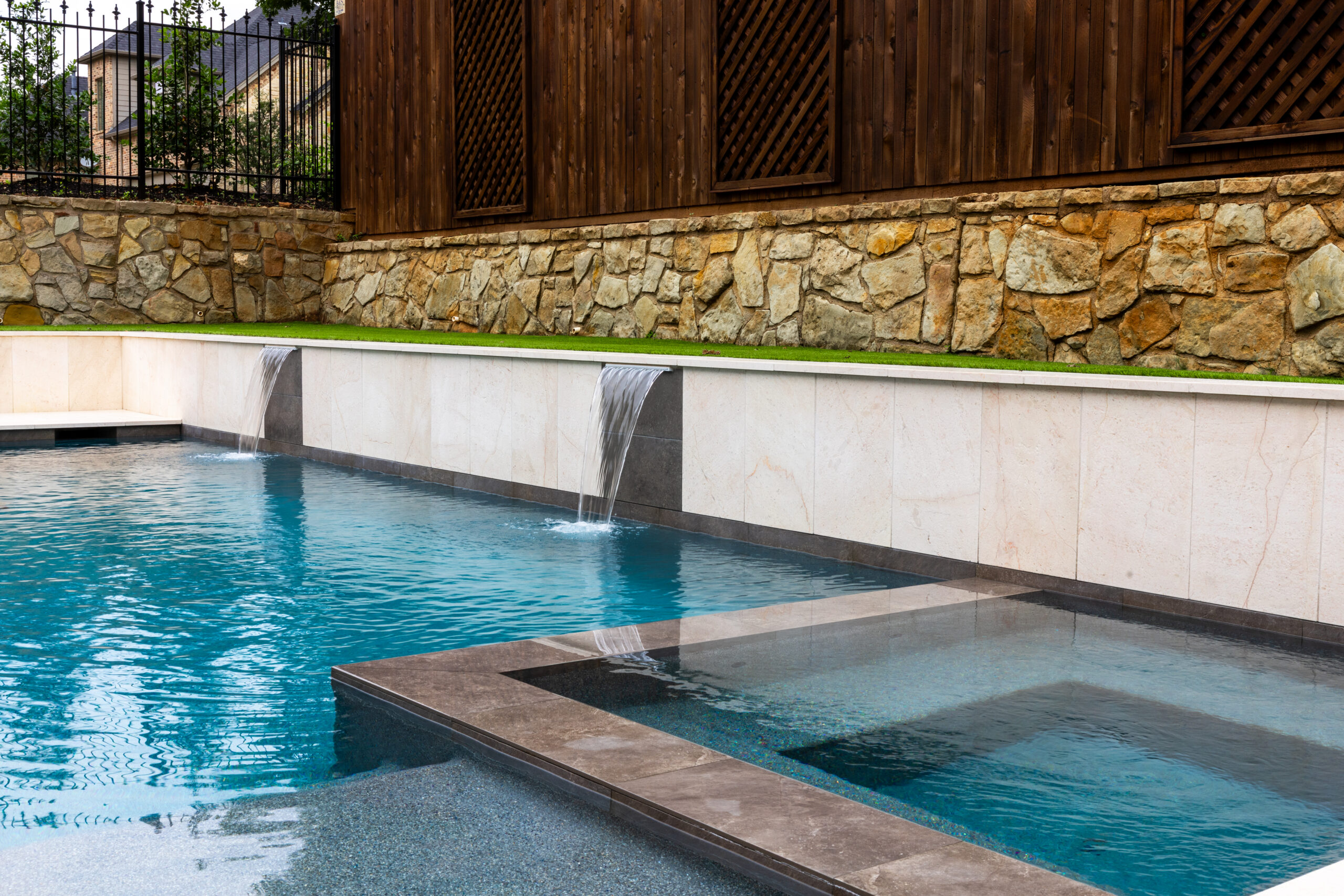 Modern swimming pool and raised spa with sheer descent water features by RiverMist Pools & Spas in Colleyville, Texas.