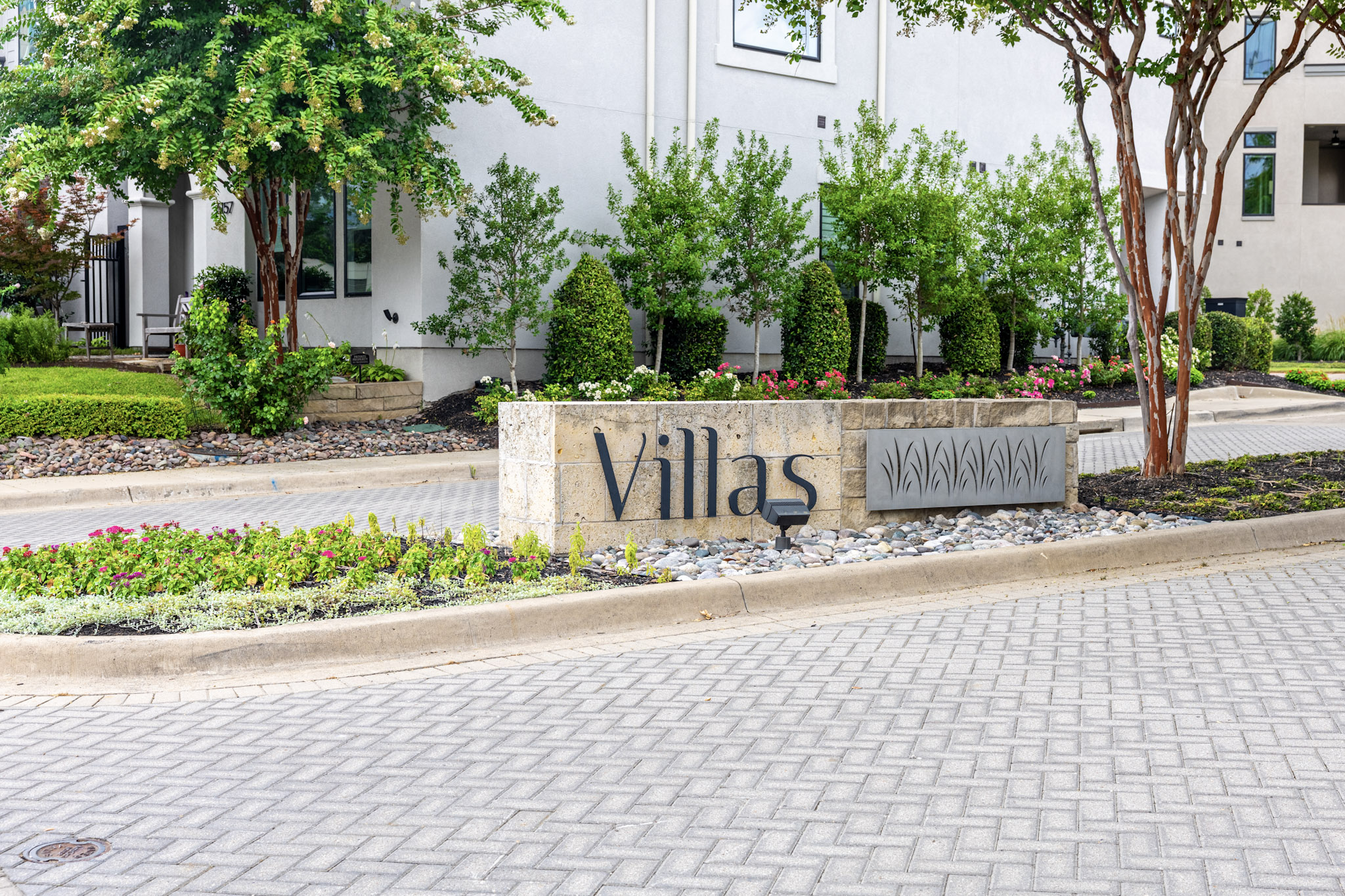 The Villas entrance sign with landscaped flower beds and mature trees.