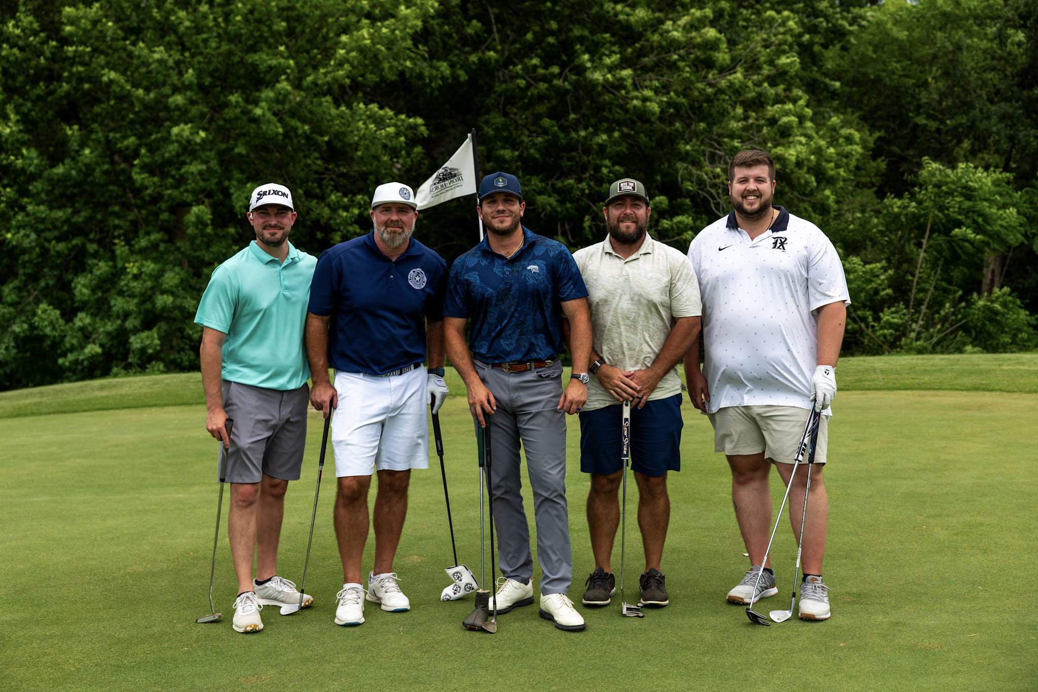 Five golfers posing together on a putting green at the LoneStar Exteriors Classic