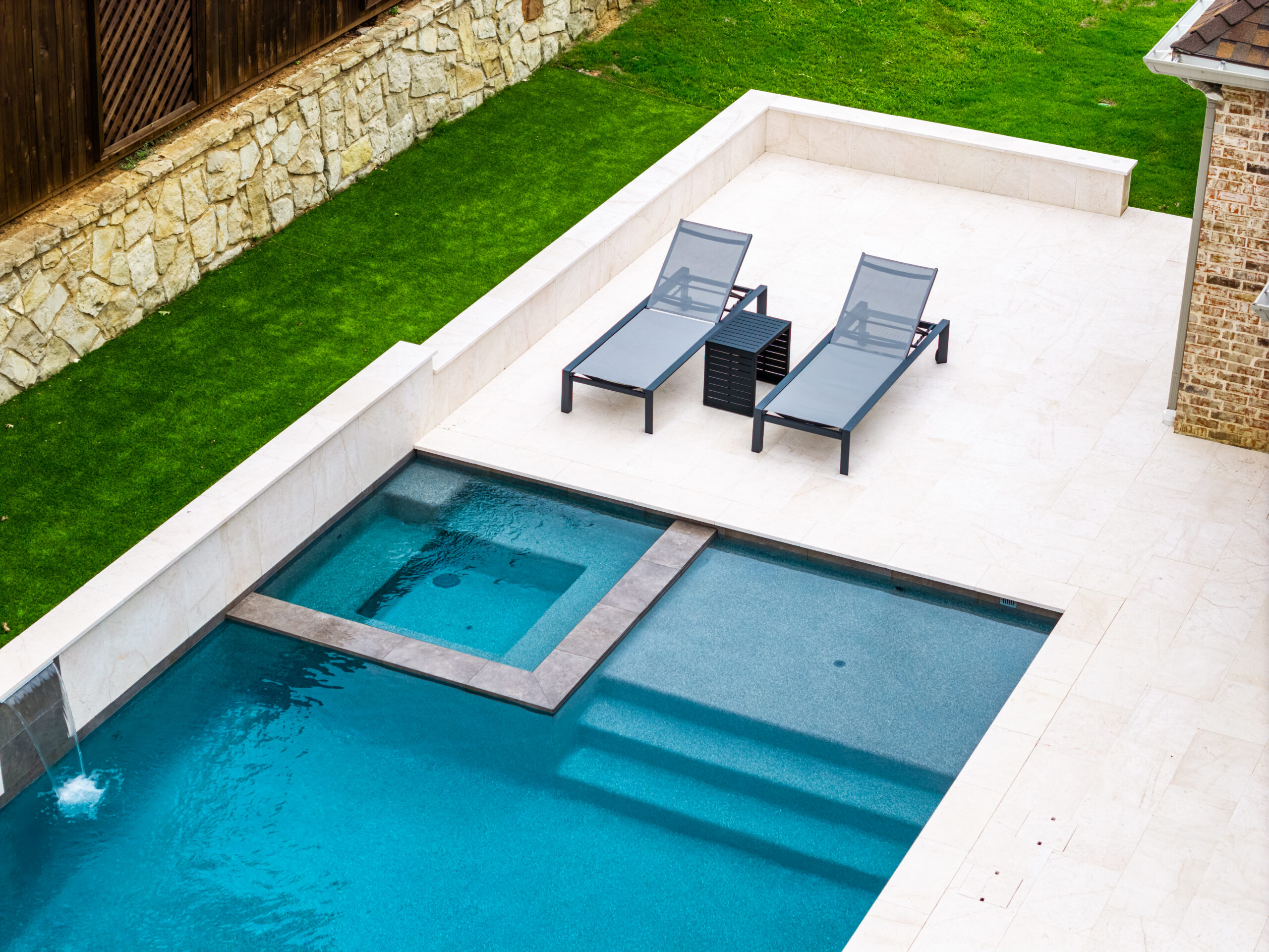 Integrated pool spa with lounge area and sheer descent waterfall at a RiverMist Pools & Spas project in Colleyville.