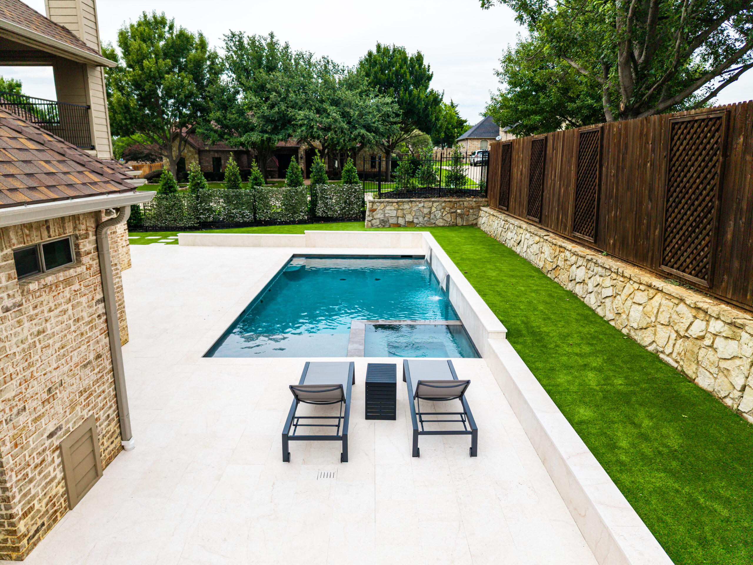 Modern swimming pool with integrated spa and dual sheer descent waterfalls by RiverMist Pools & Spas in Colleyville, Texas.