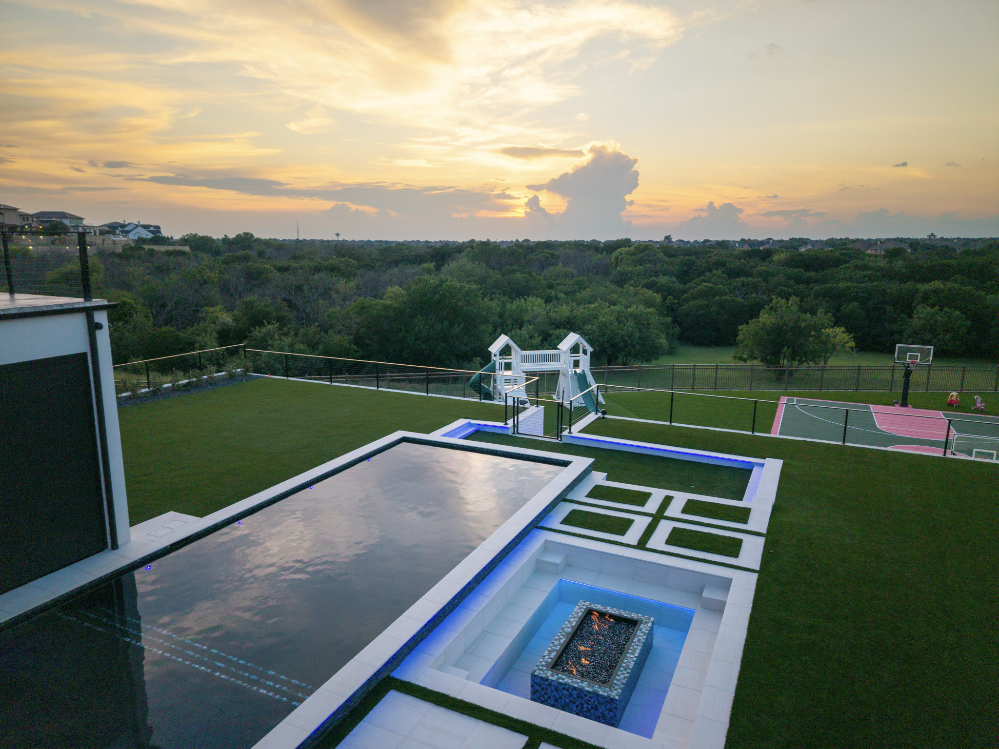 Luxury pool, fire pit and sport court overlooking a sunset.