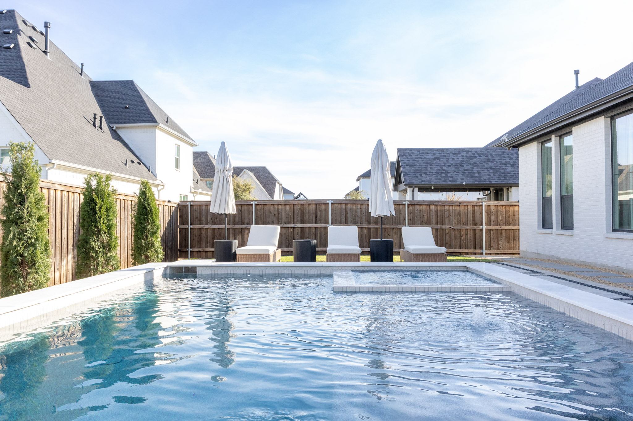 Rectangular pool with shallow ledge, bubbler, square spa and three lounge chairs.