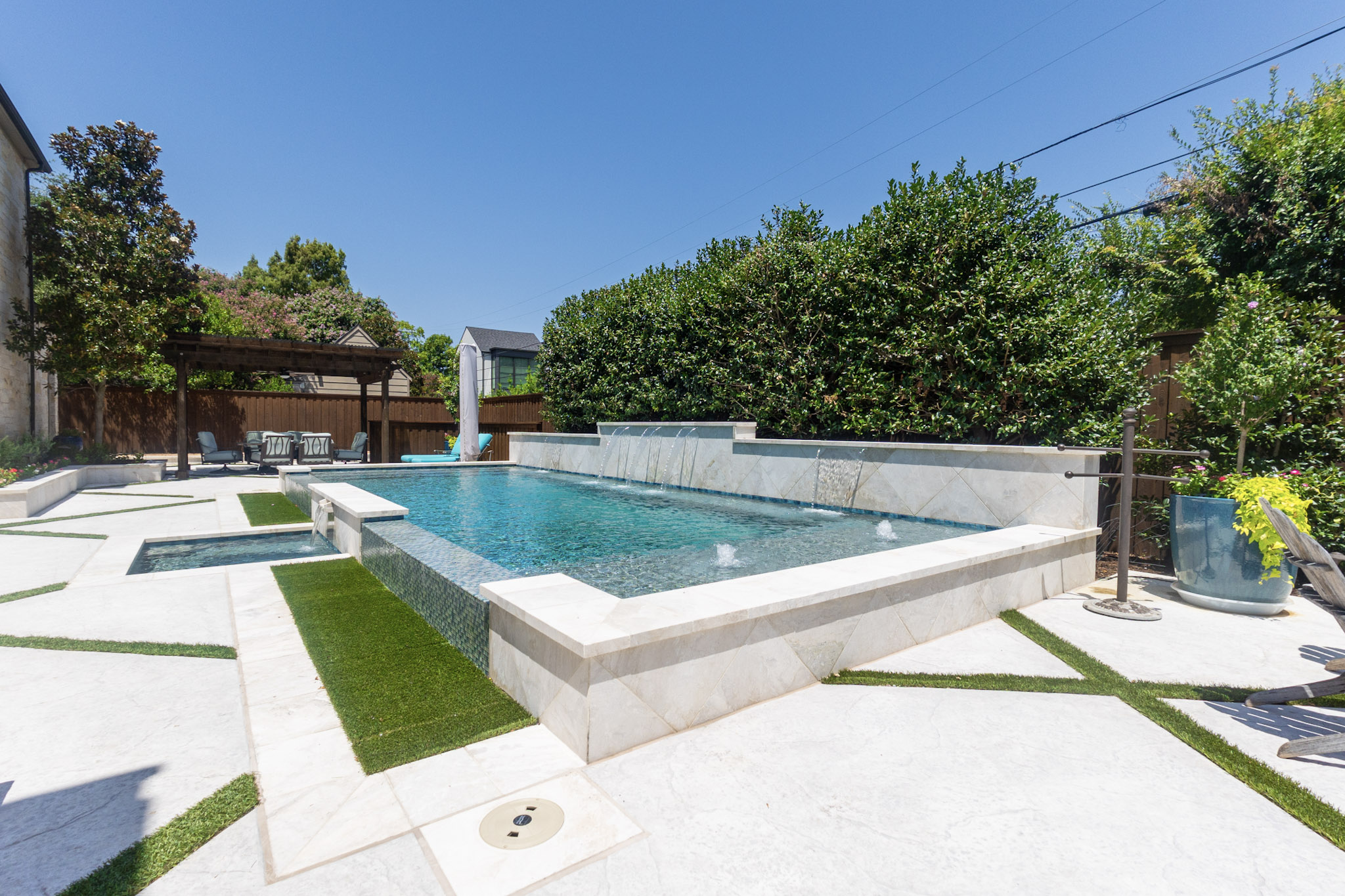 Raised vanishing edge pool with spa and water feature wall in University Park, TX