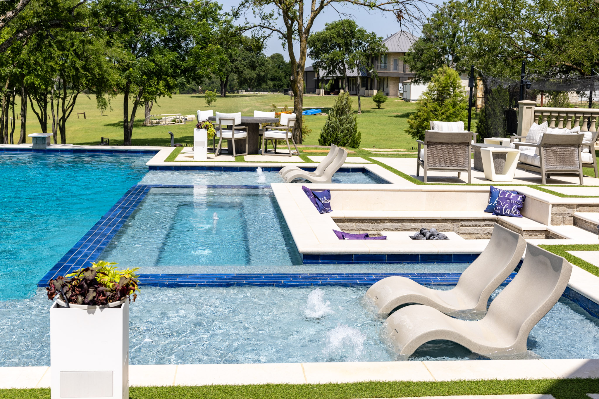 Custom pool tanning ledge with loungers, spa and fire pit in Lakewood Village, Texas