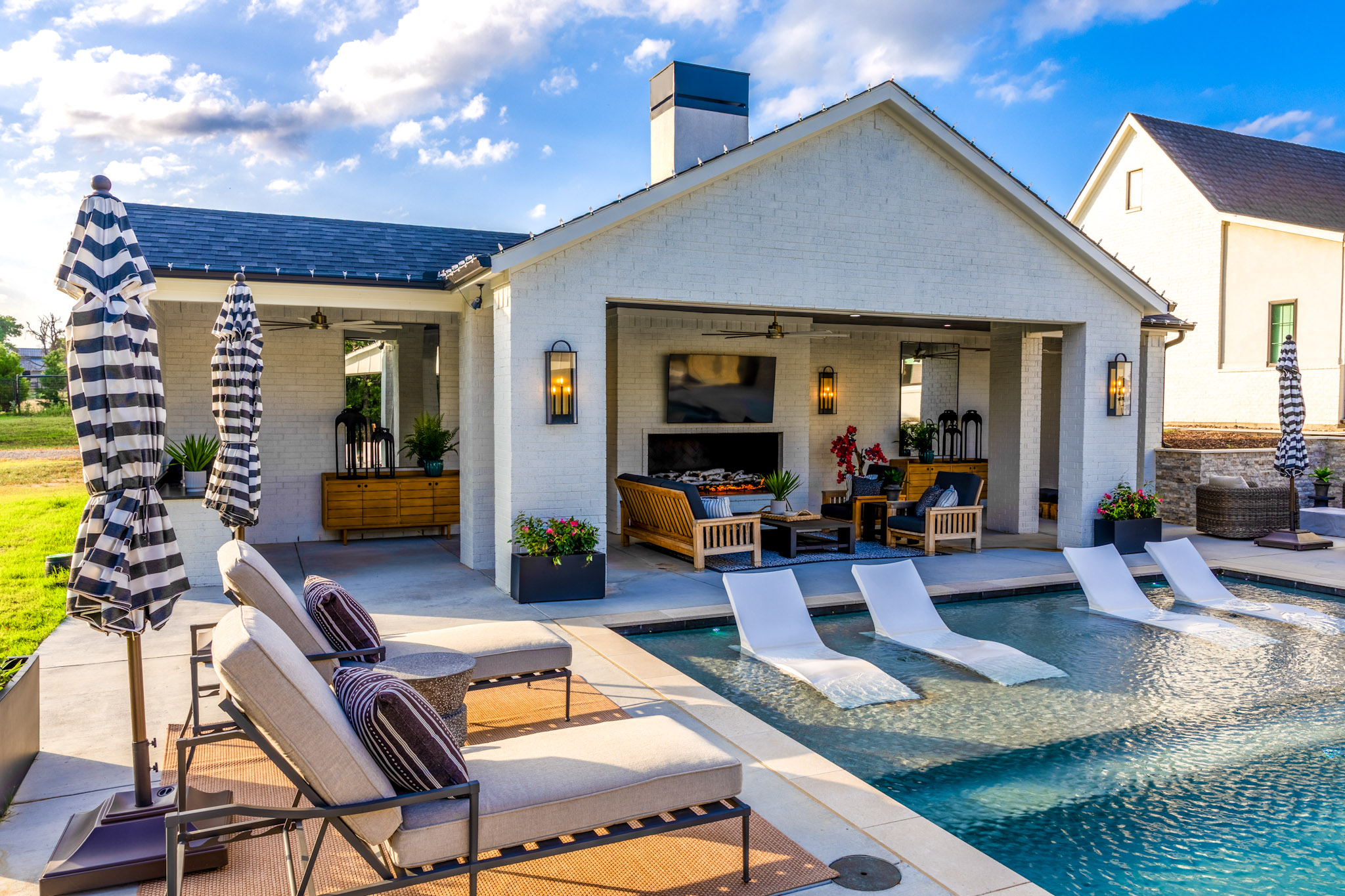 Luxury pool with submerged loungers and covered fireplace patio in Weatherford.