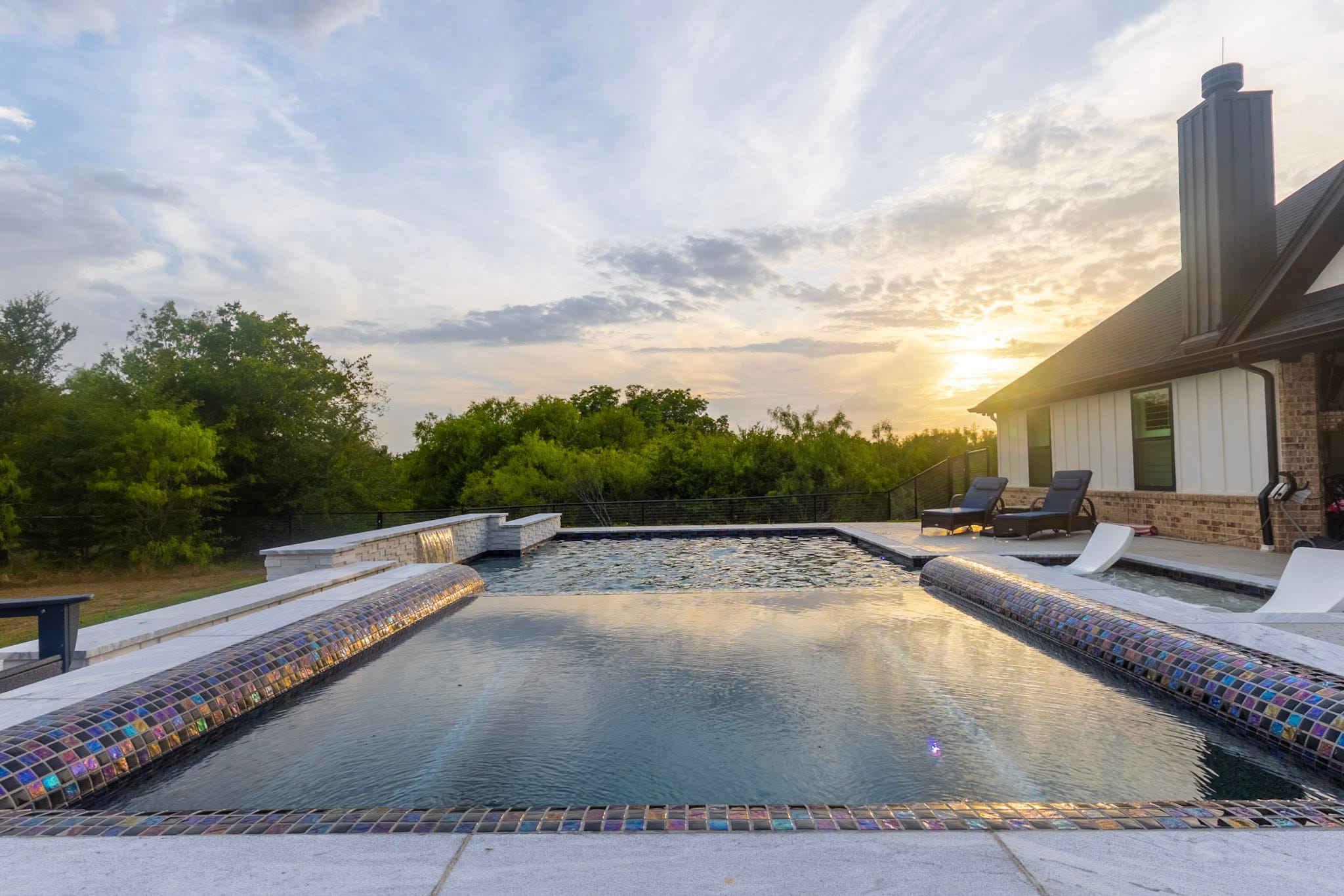 Warm sunset light reflects across the raised spa and main swimming pool.