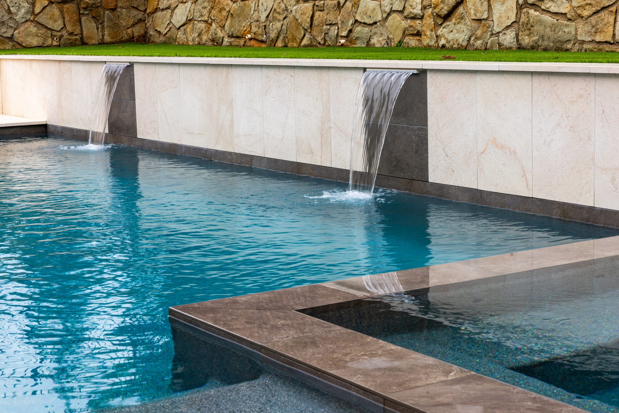 Modern swimming pool with integrated spa and dual sheer descent waterfalls by RiverMist Pools & Spas in Colleyville, Texas.