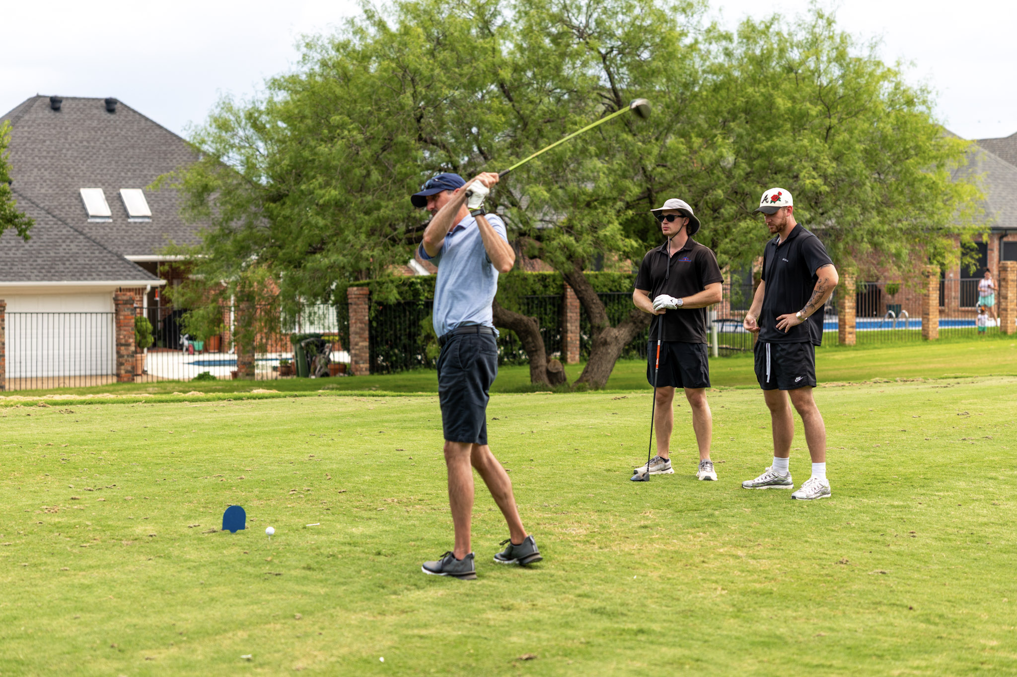 Golfer taking a tee shot while two other golfers watch