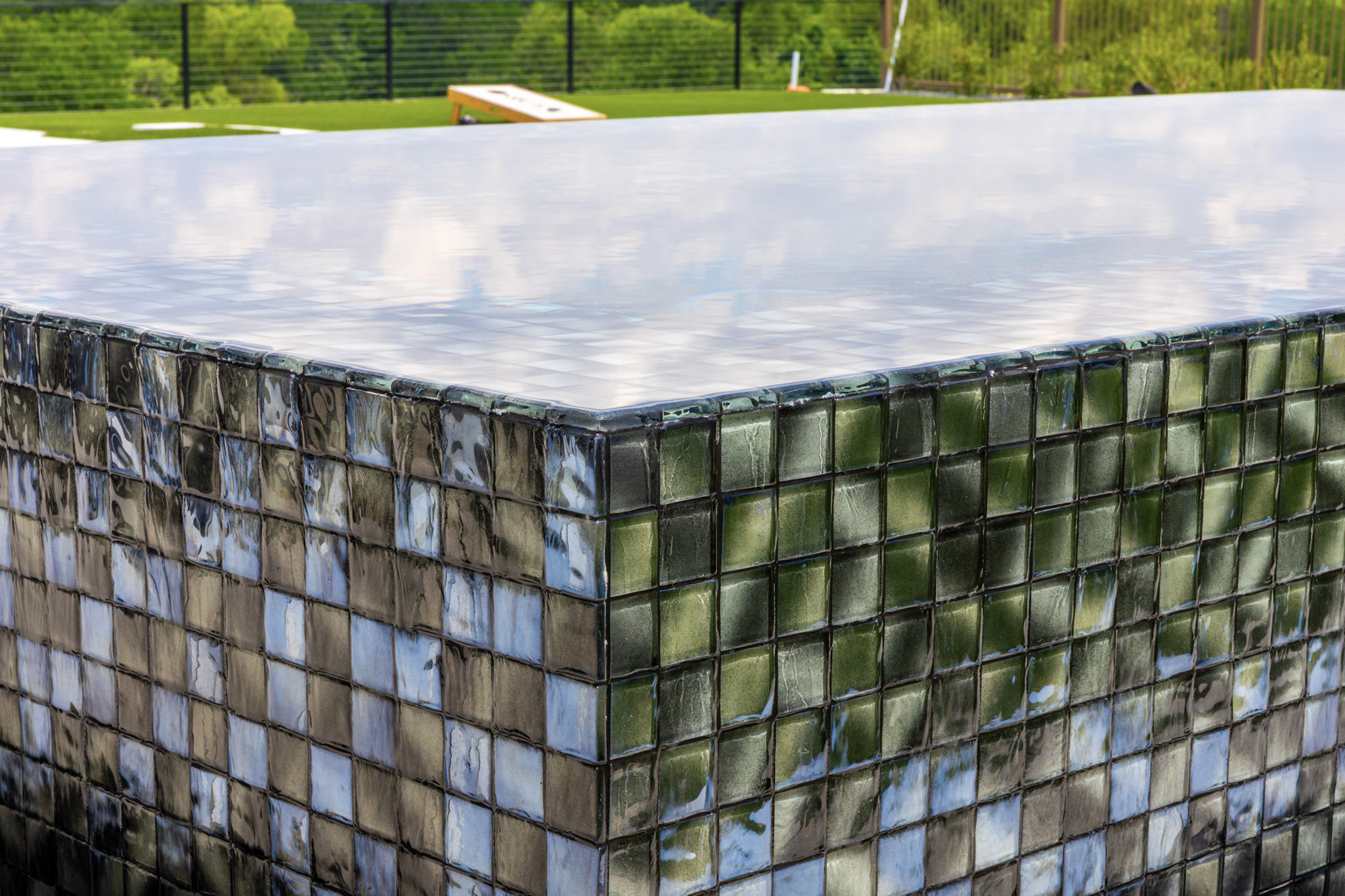 Close-up of reflective square glass tile on a raised pool spa.