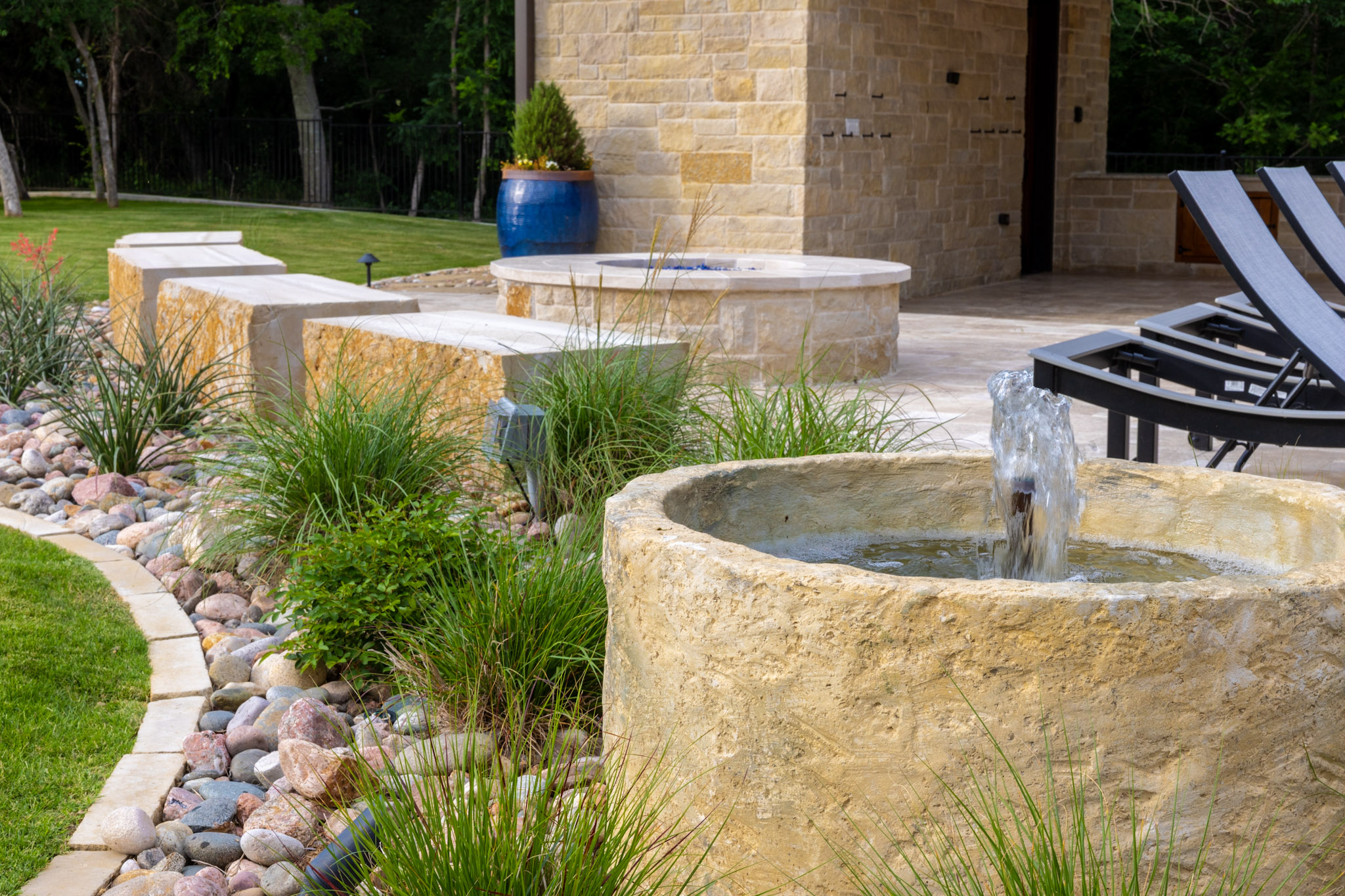 Custom landscape fountain surrounded by ornamental grasses and stone landscaping in Weston, TX