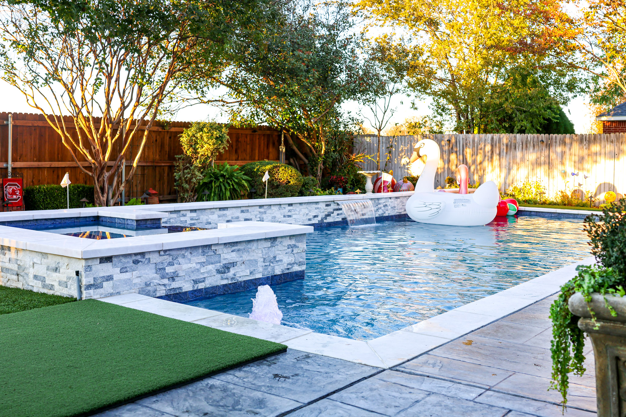 Rectangular pool with raised square spa, sheer descent and artificial-turf putting green.