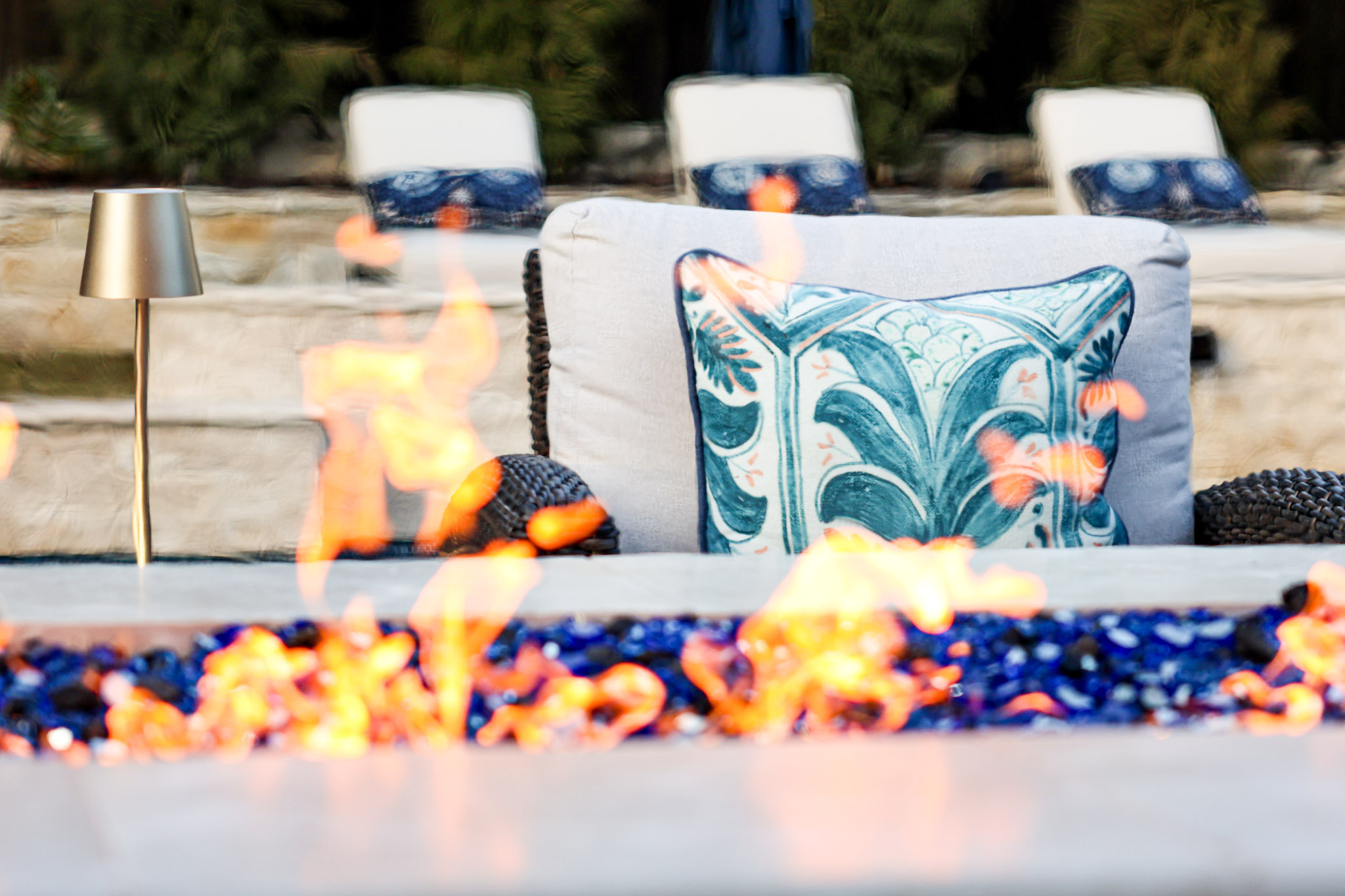 Close view of flames beside cushioned poolside seating in Fort Worth.
