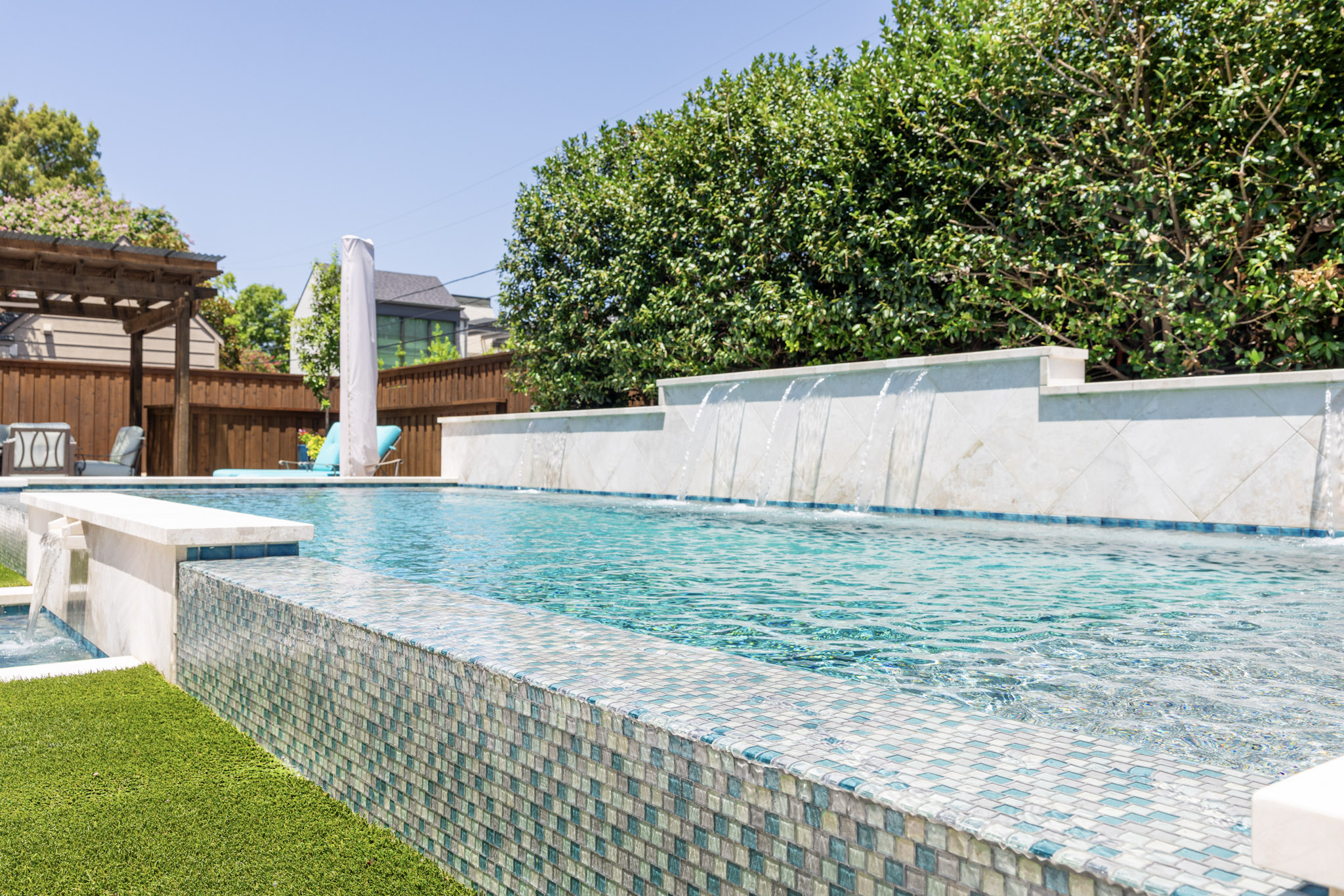 Vanishing edge pool with glass tile and raised sheer descent water features