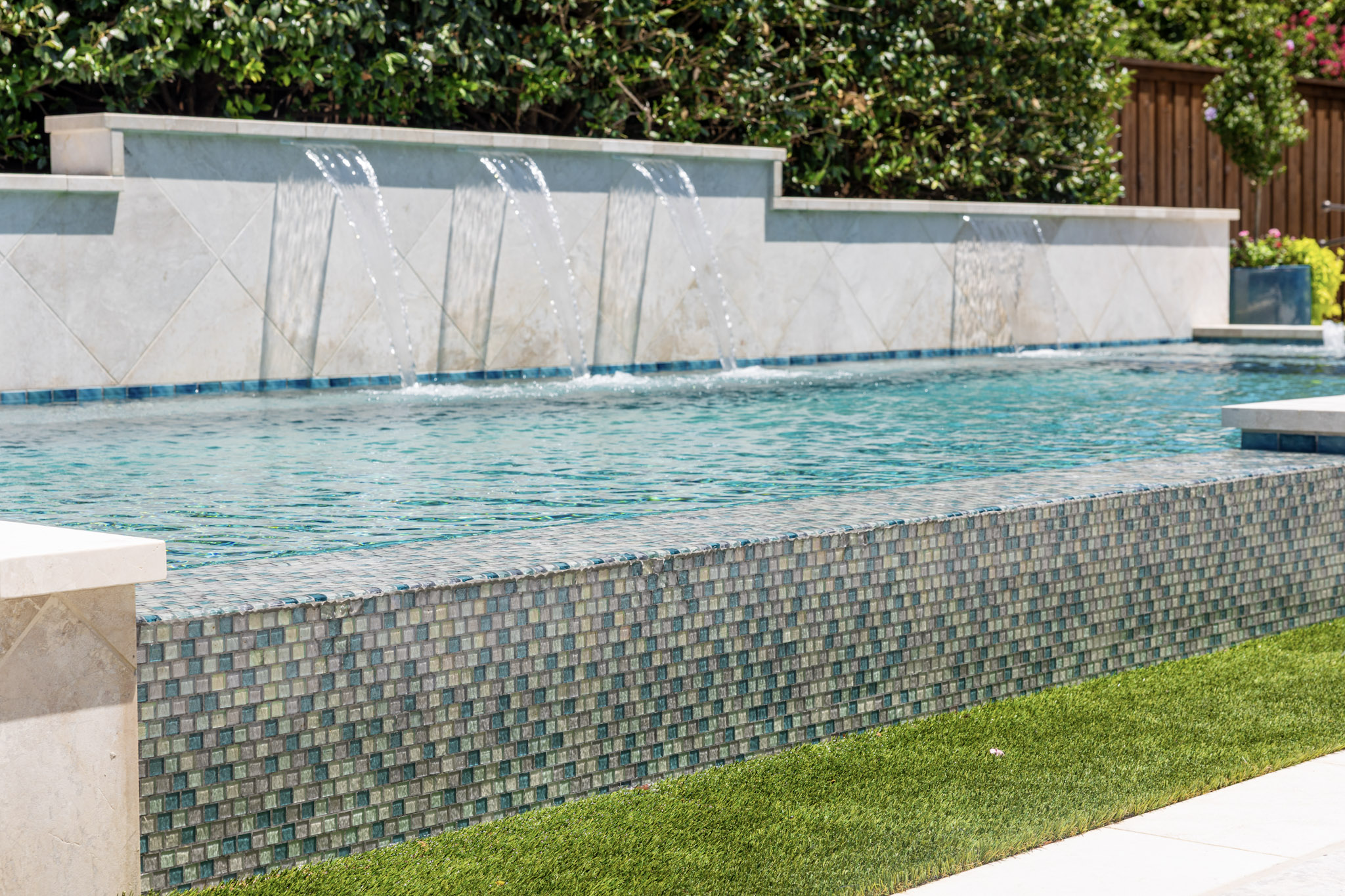 Glass mosaic vanishing edge pool with raised water features in University Park, Texas
