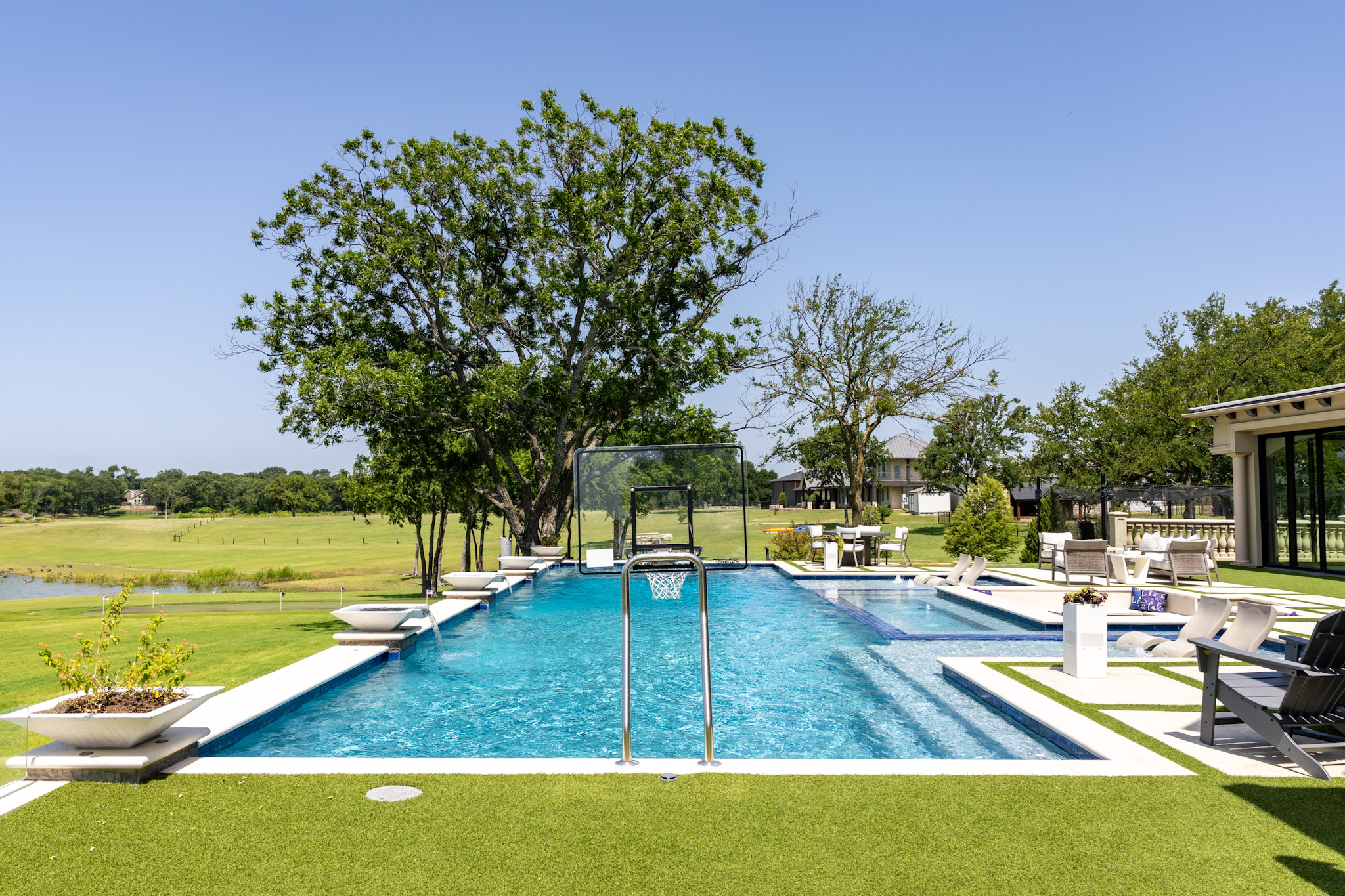 Large lakefront custom swimming pool with basketball goal in Lakewood Village, TX