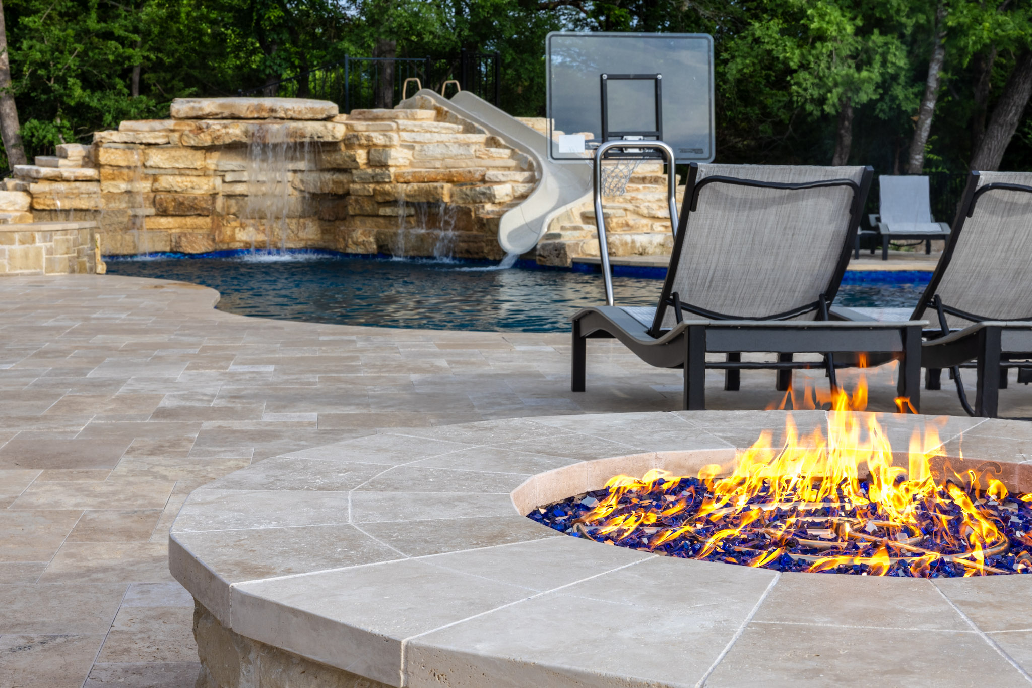 Stone fire pit overlooking custom pool and waterfall in Weston, TX