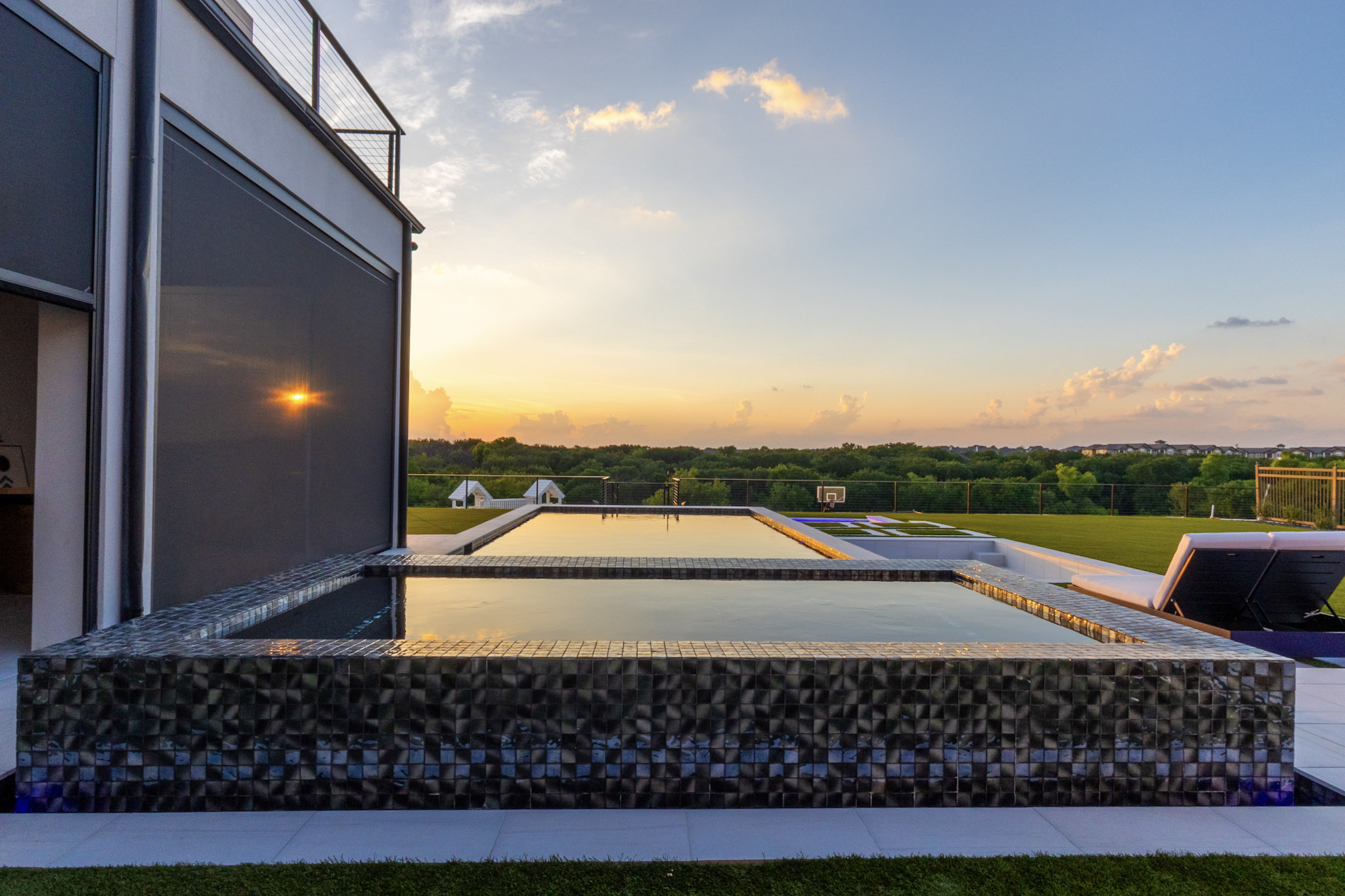 Raised glass-tile spa and pool overlooking a sunset in Frisco.