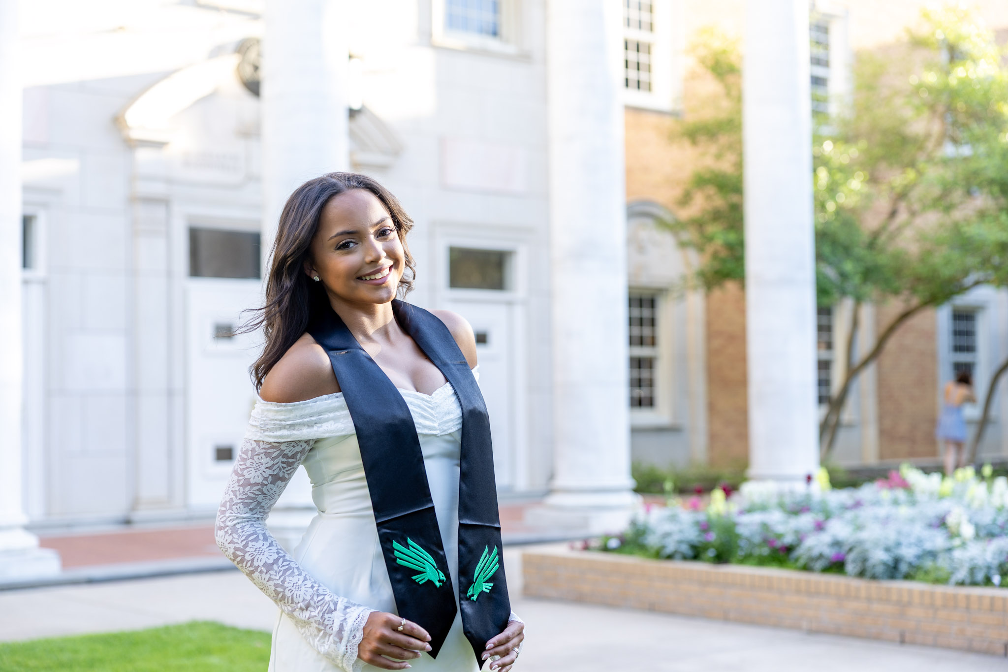 UNT graduate posing outside a columned campus building in Denton