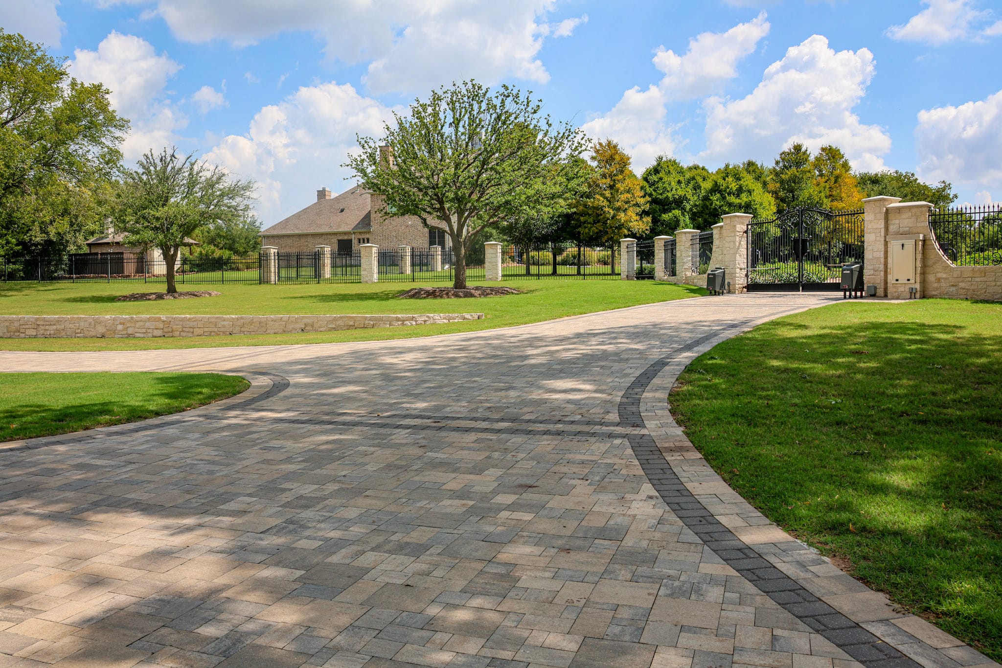 Patterned Belgard paver walkway with dark borders leading to an arched front entry.