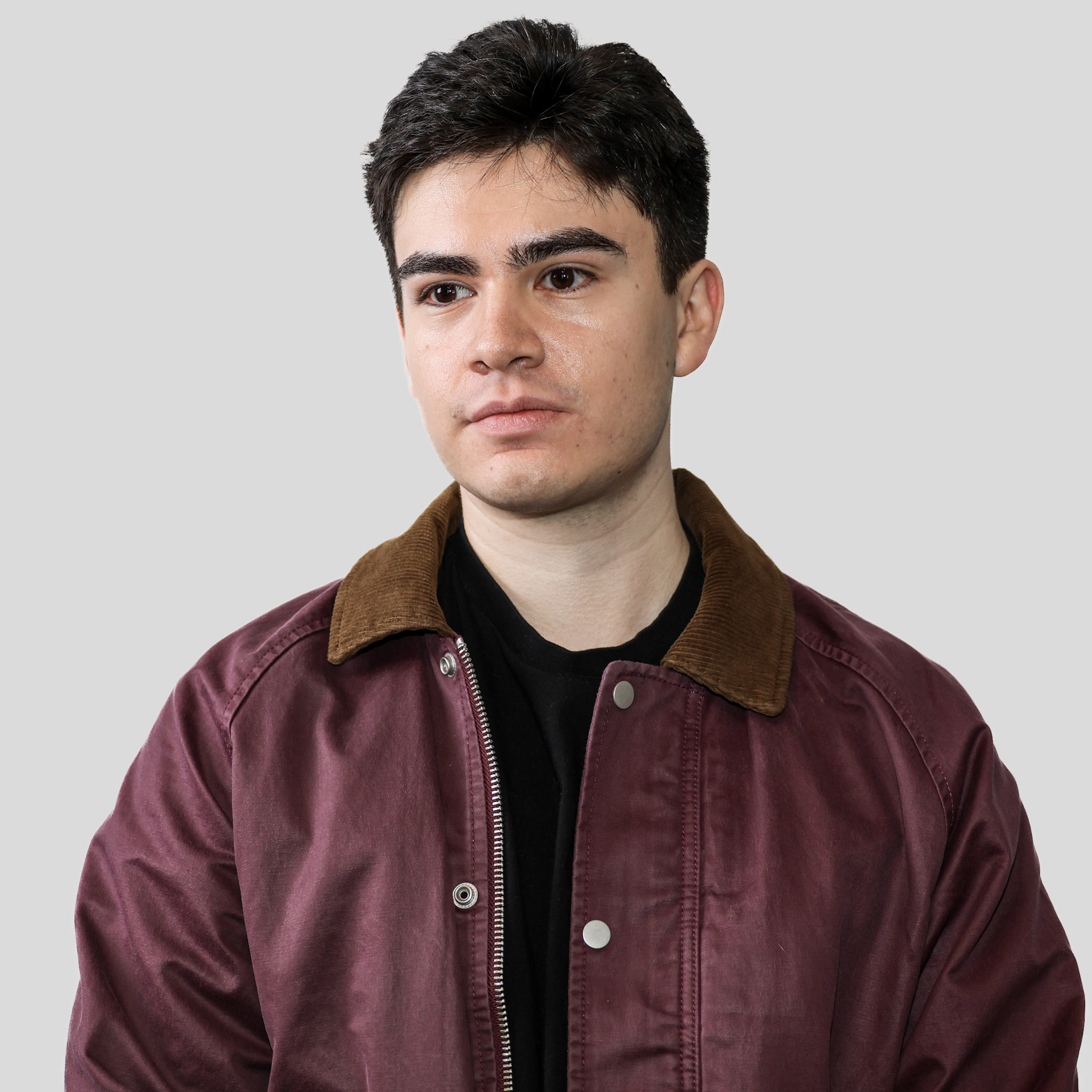 Joshua Flores wearing a burgundy jacket with a brown collar over a black shirt.
