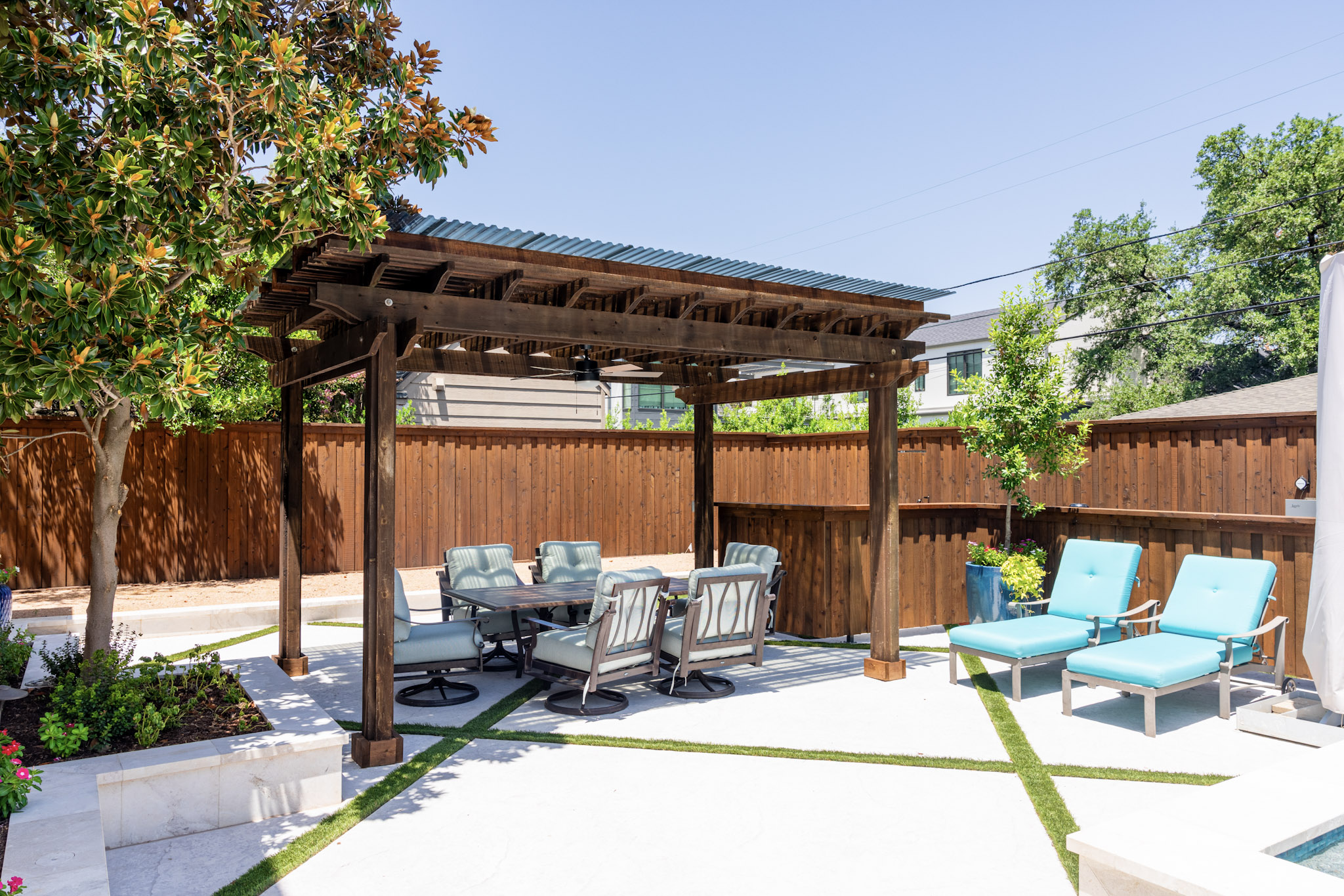 Wood pergola and outdoor seating area beside custom swimming pool