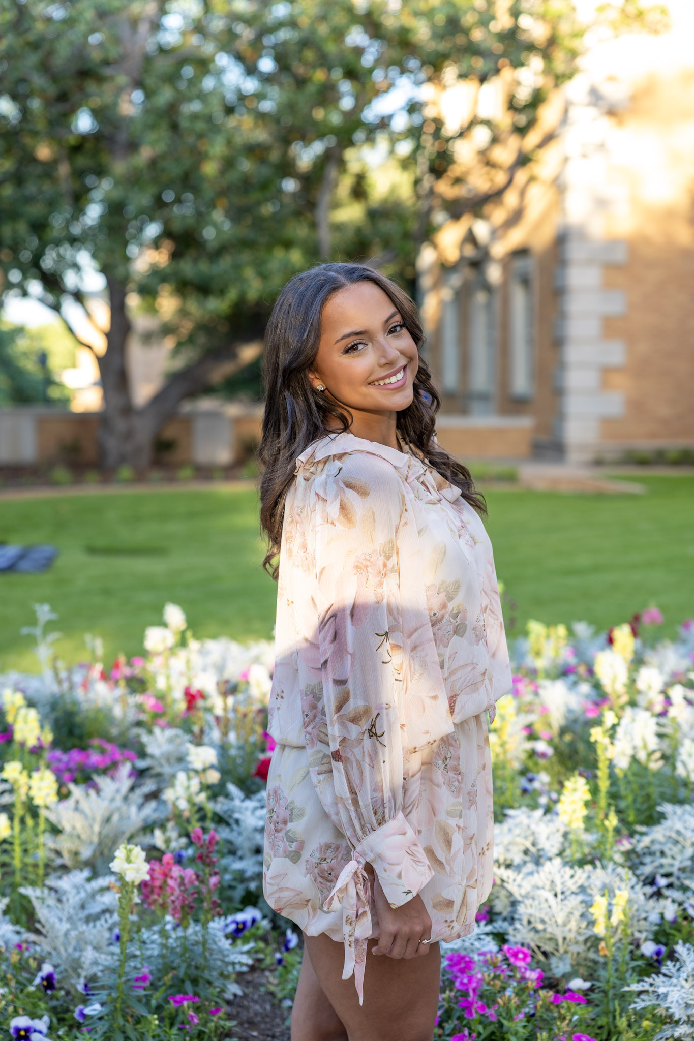 Skylar Allen standing beside colorful flowers on the UNT campus