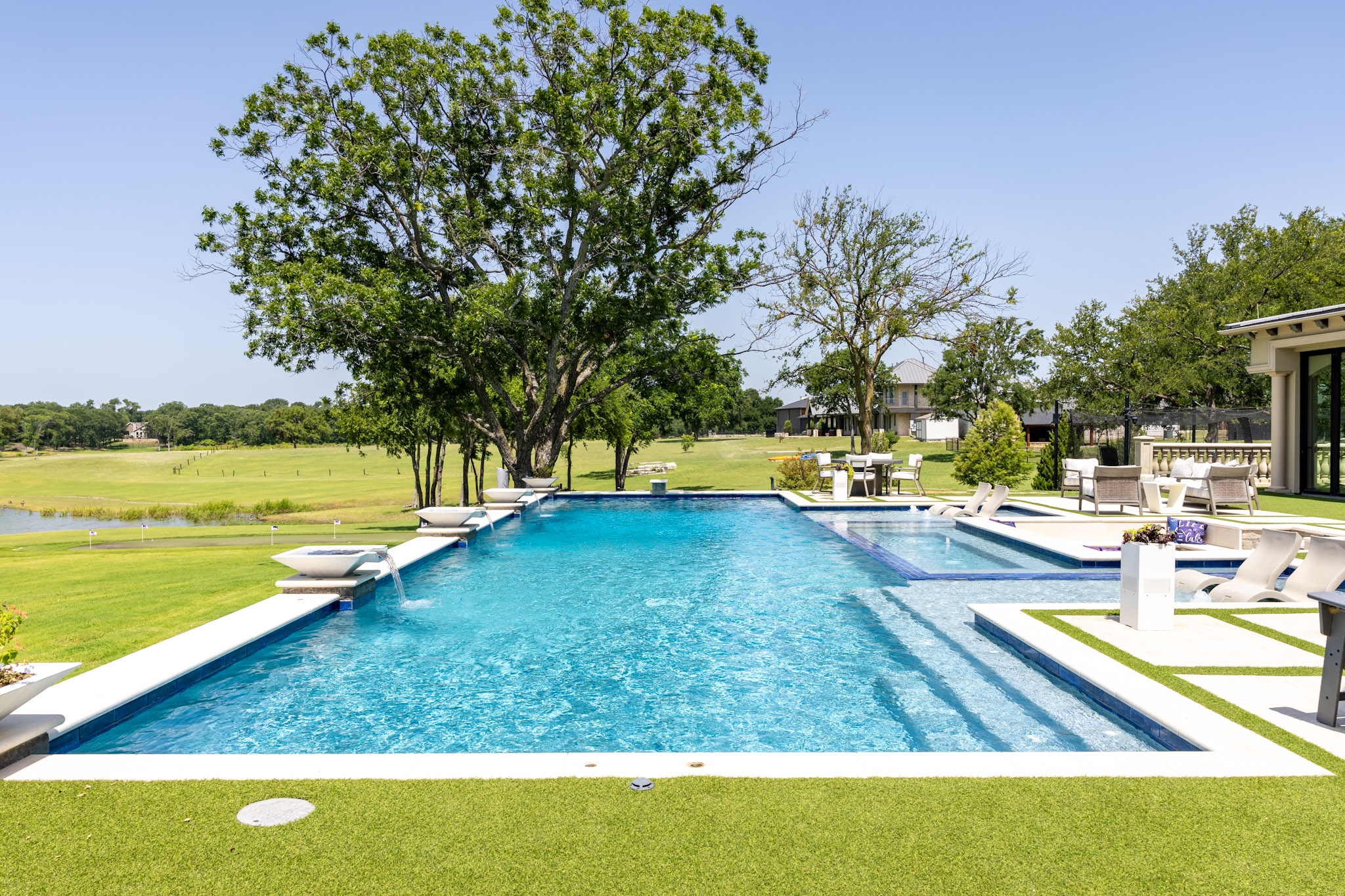 Large custom swimming pool with tanning ledge and water features in Lakewood Village, TX