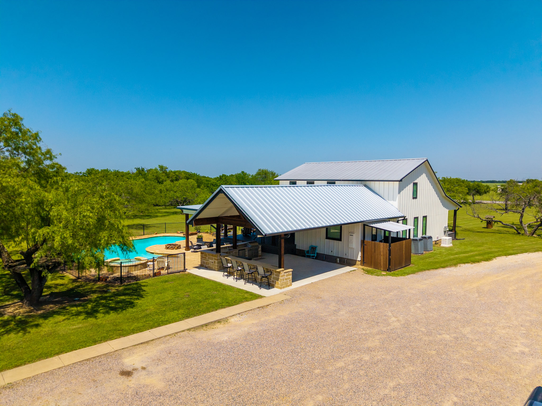 Elevated view of a light-colored home with metal roofs, covered patio and backyard pool.