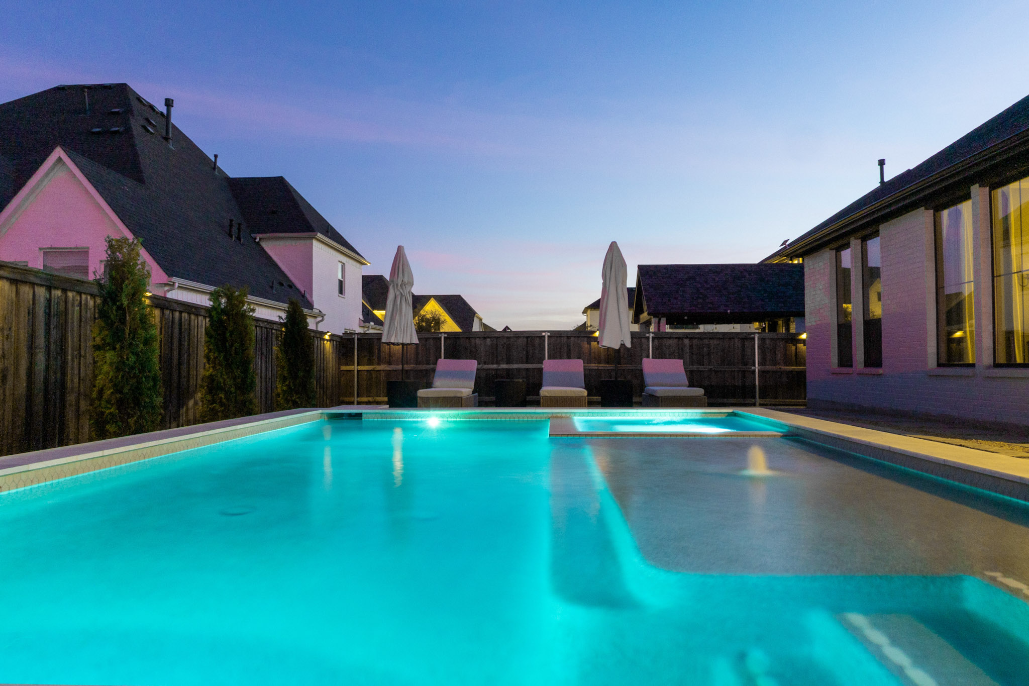 Blue-lit pool with broad shallow ledge and active bubbler at twilight.