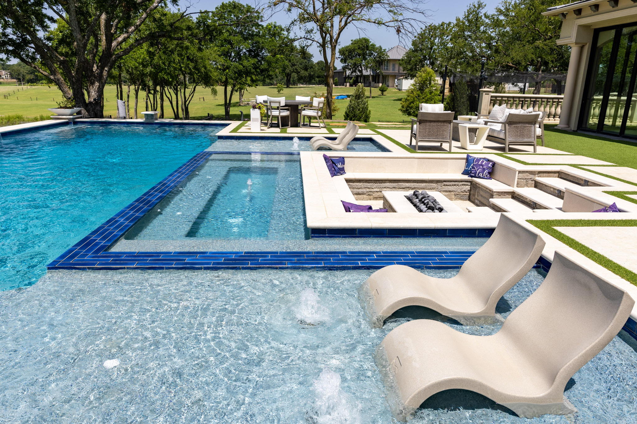 Tanning ledge with in-pool loungers and sunken fire pit at Lakewood Village custom pool