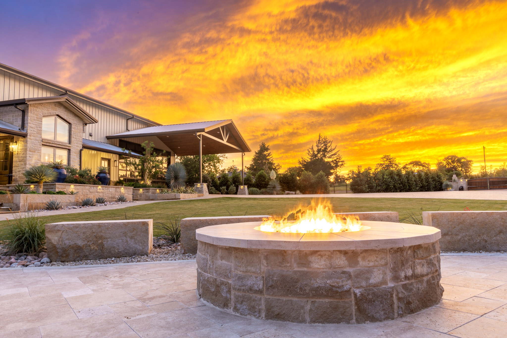 Custom stone fire pit and landscaped backyard at sunset in Weston, Texas