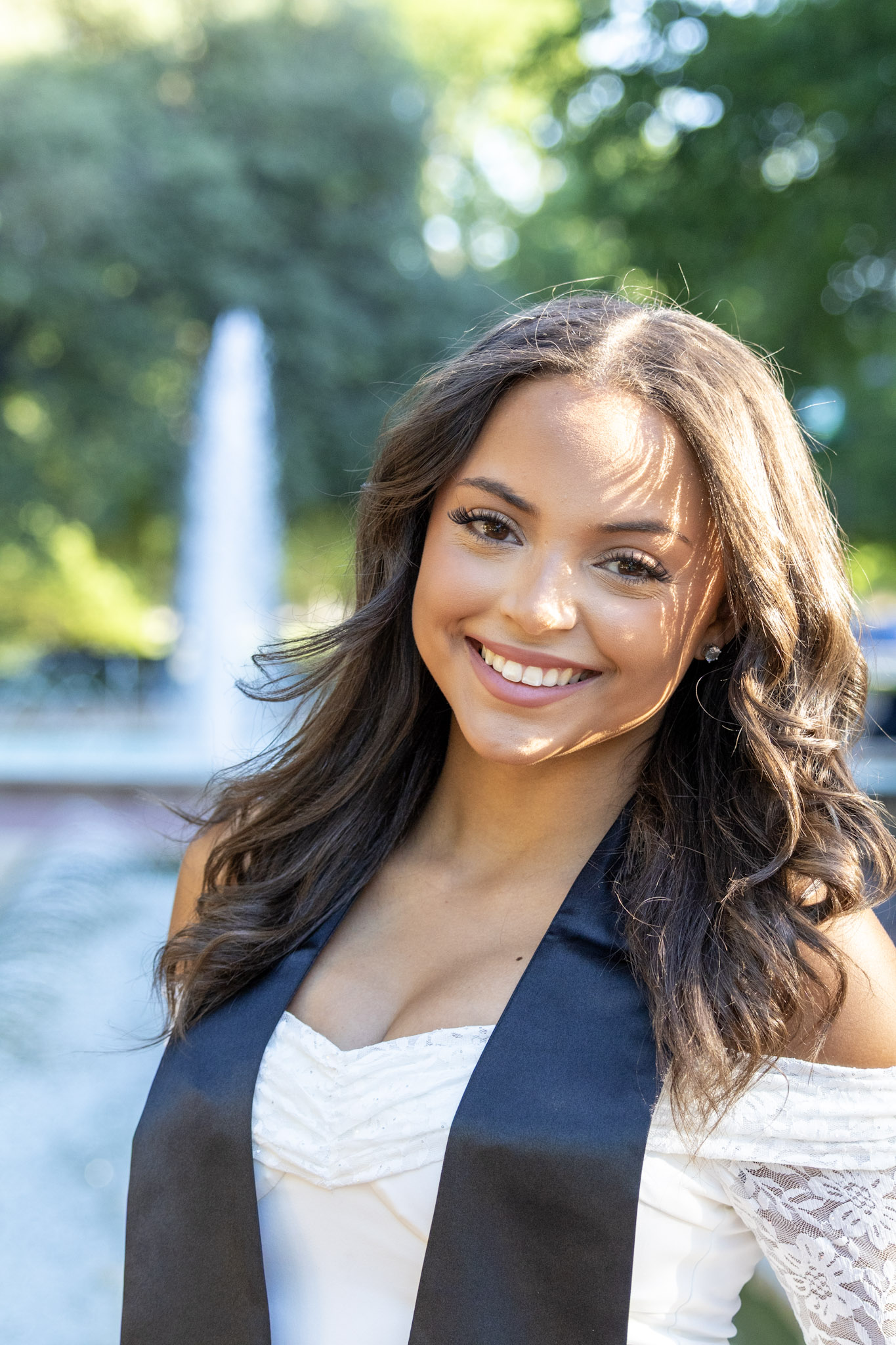 Close-up portrait of a UNT graduate with a fountain in the background