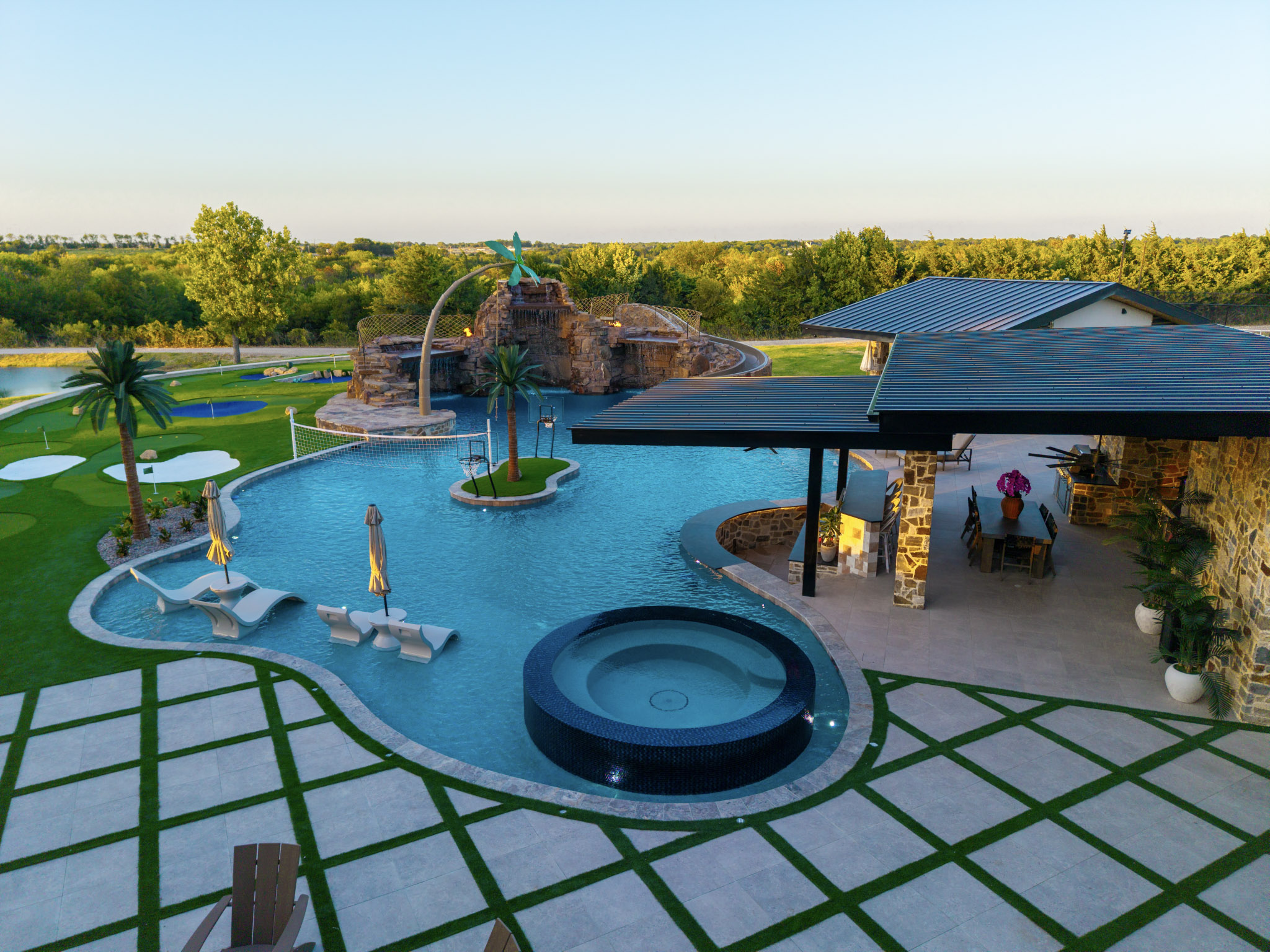 Elevated view of resort pool with round spa, waterfall and outdoor pavilion.