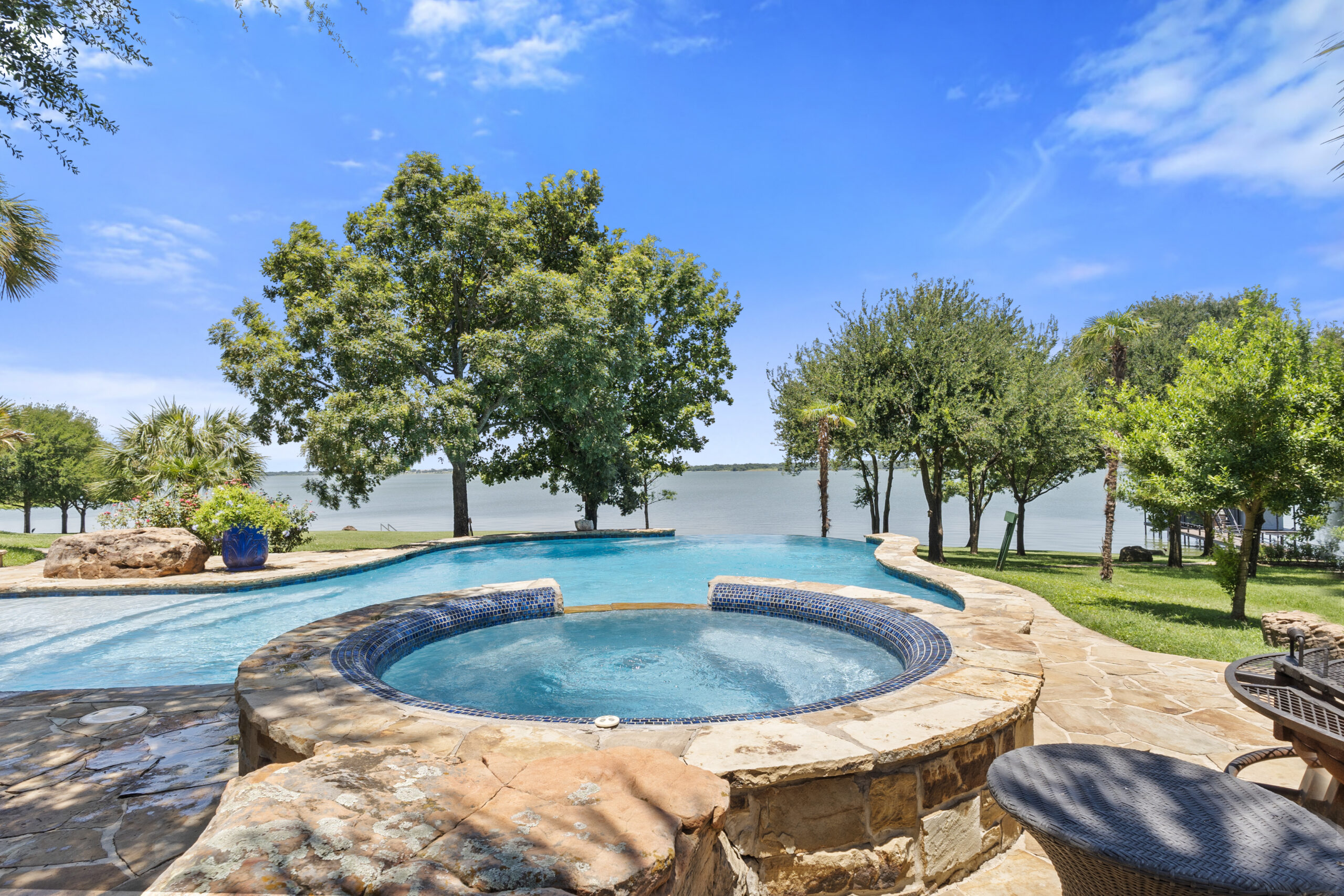 Raised circular spa overlooking a freeform pool and lake in Corsicana, Texas.