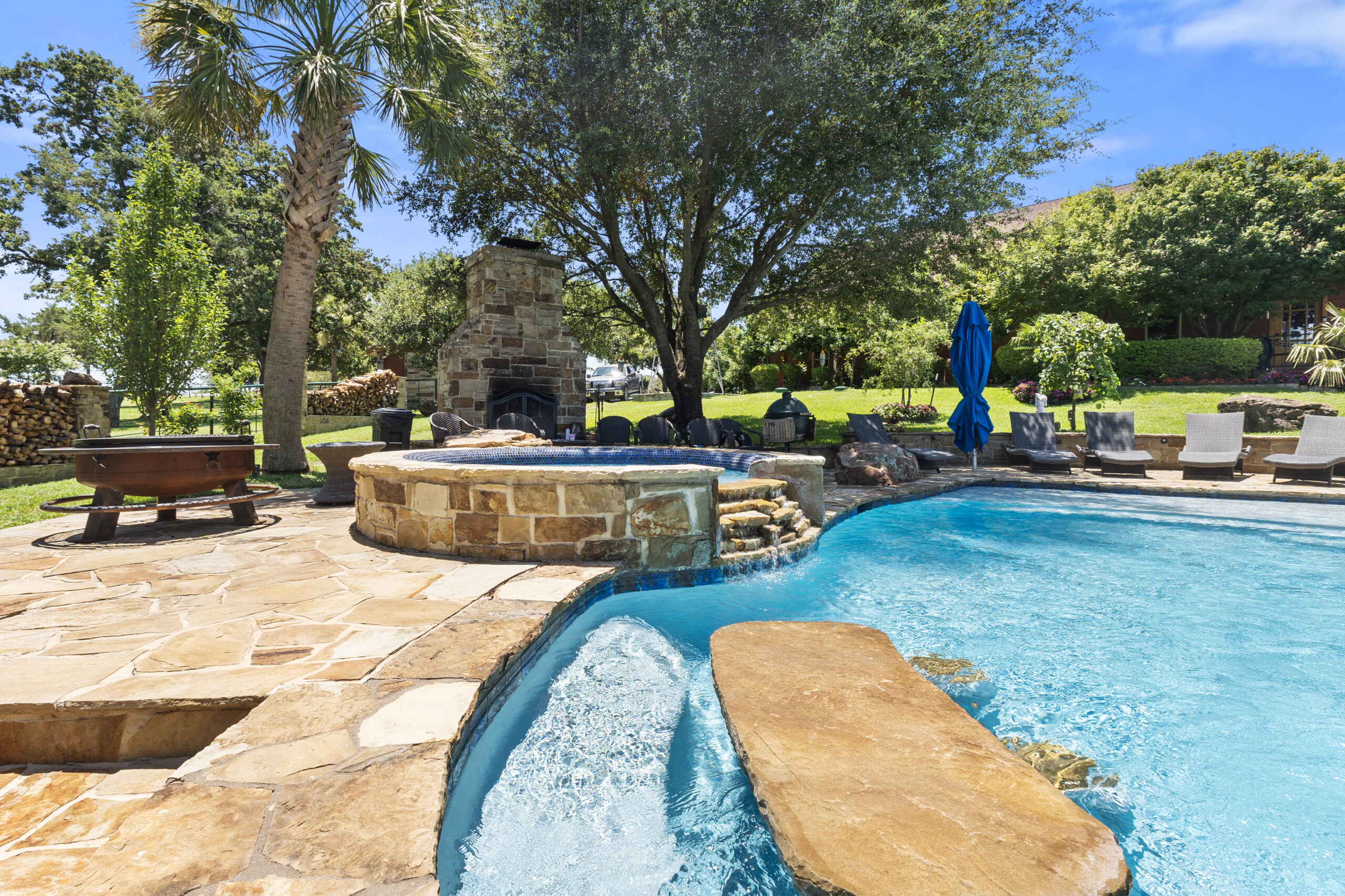 Raised stone spa beside a freeform pool with natural stone steps and rock features.