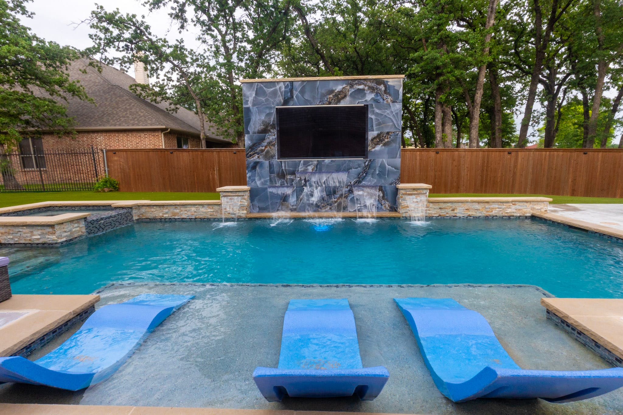 Wide custom pool with porcelain water wall spa and covered outdoor living