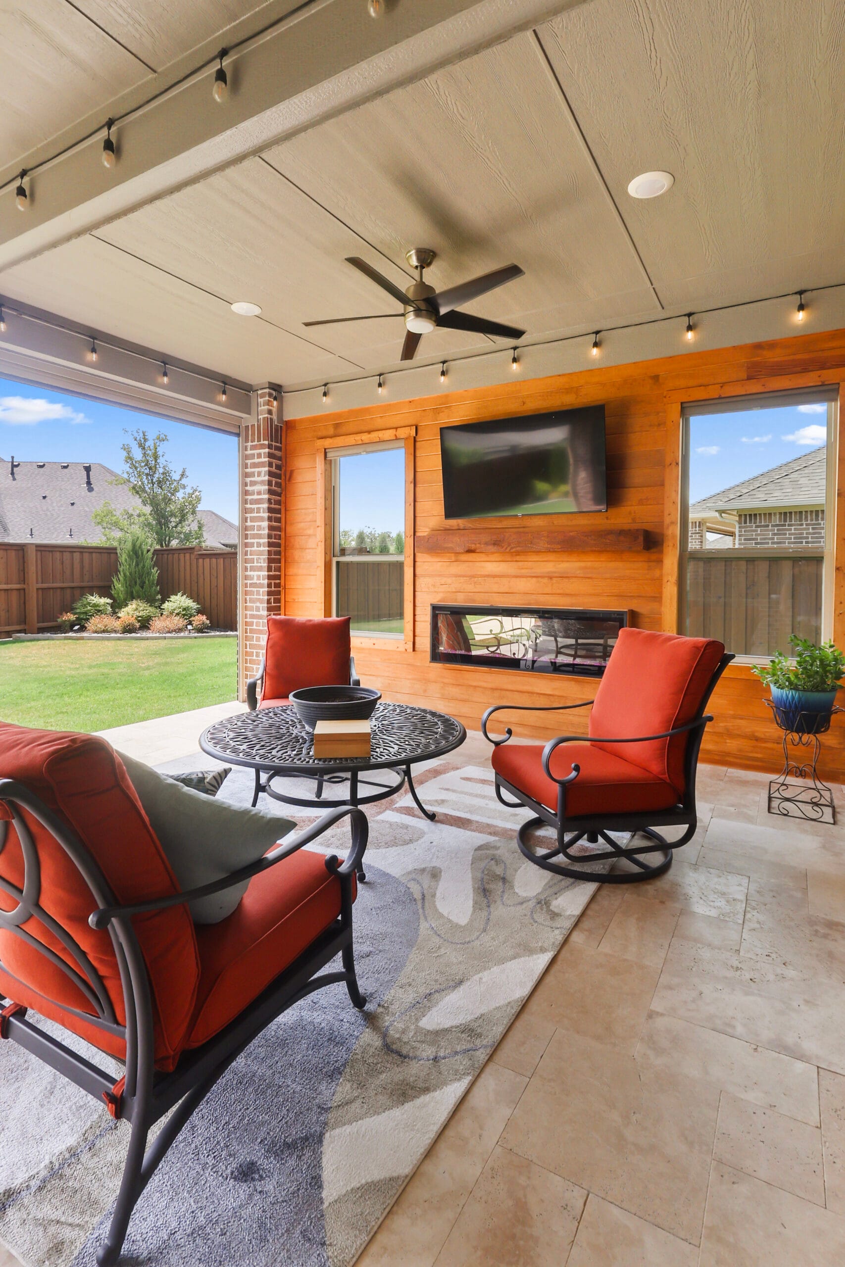 Vertical view of a furnished covered patio with fireplace and television