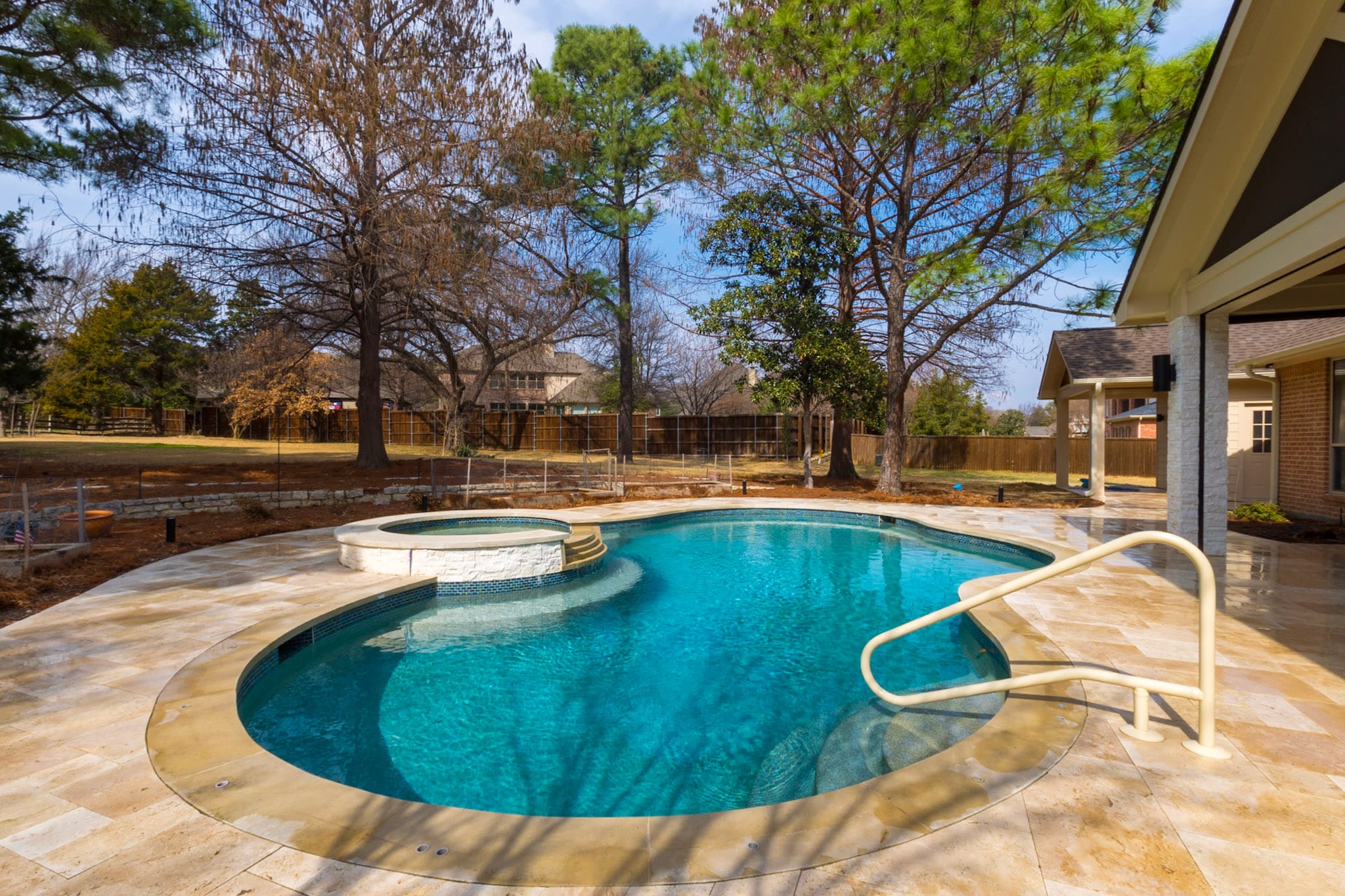 Remodeled freeform pool and raised spa with travertine decking