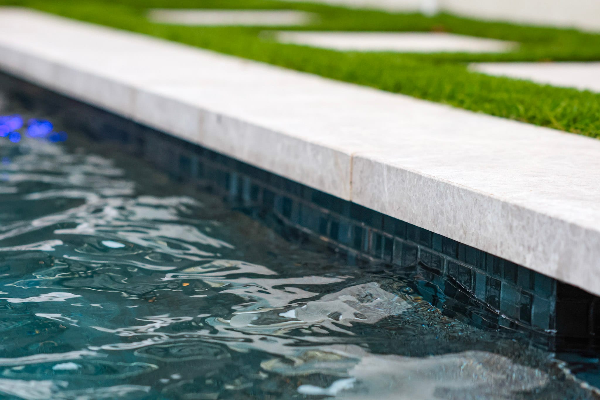 Close view of light pool coping above dark waterline tile