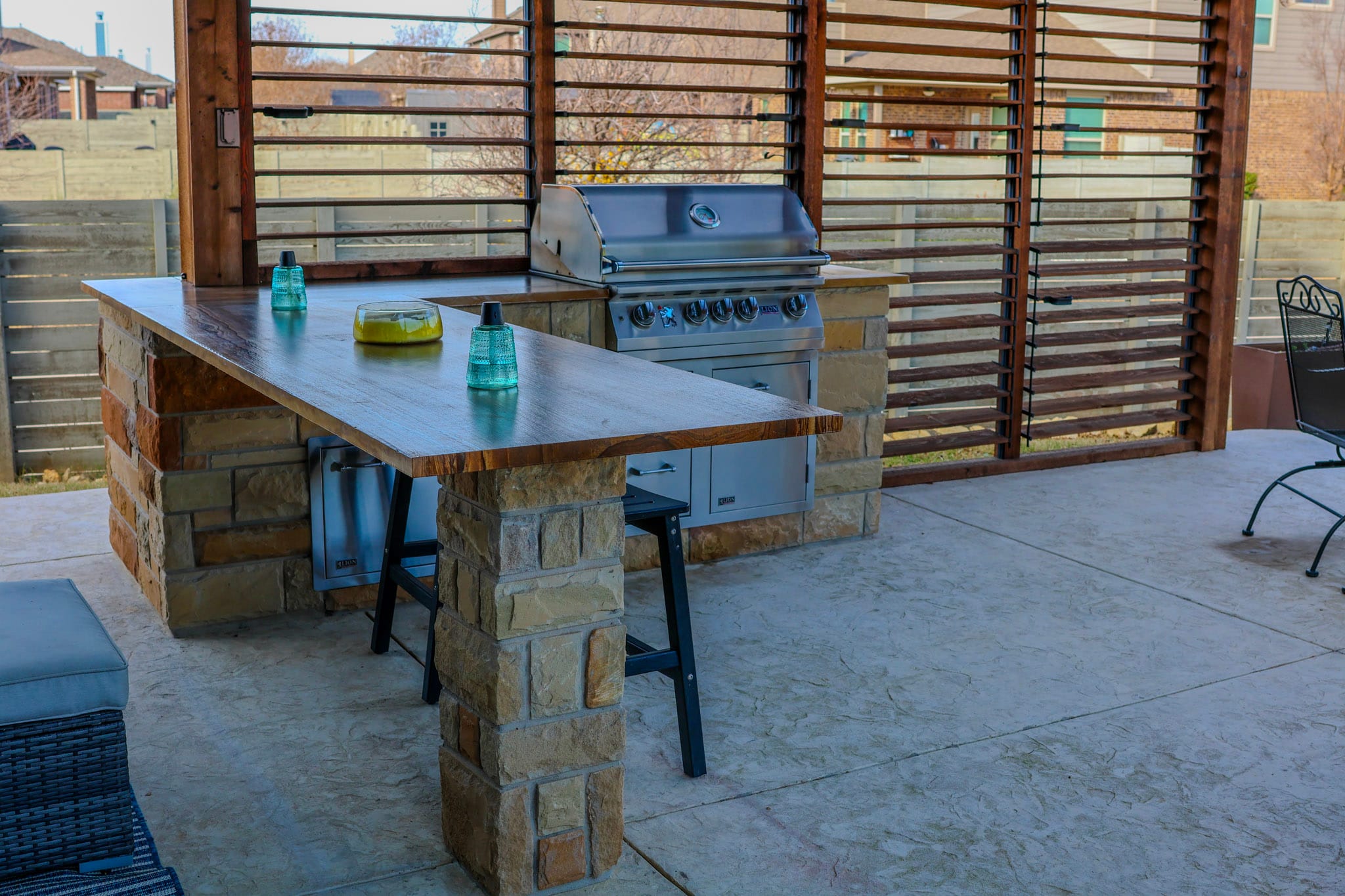 Built-in outdoor kitchen with grill, wood bar top, and stone columns