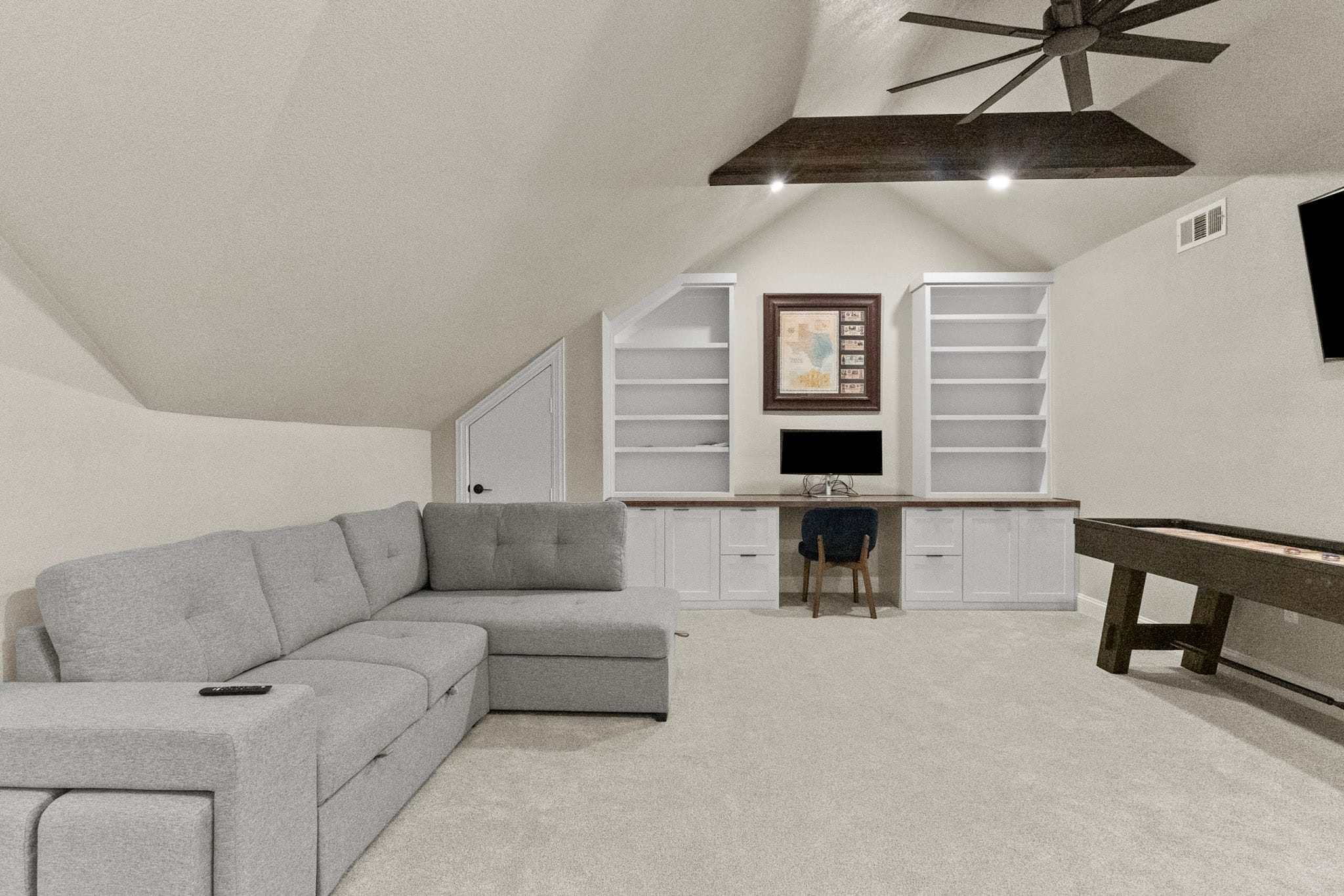 Finished attic entertainment room with built-in desk and vaulted ceiling