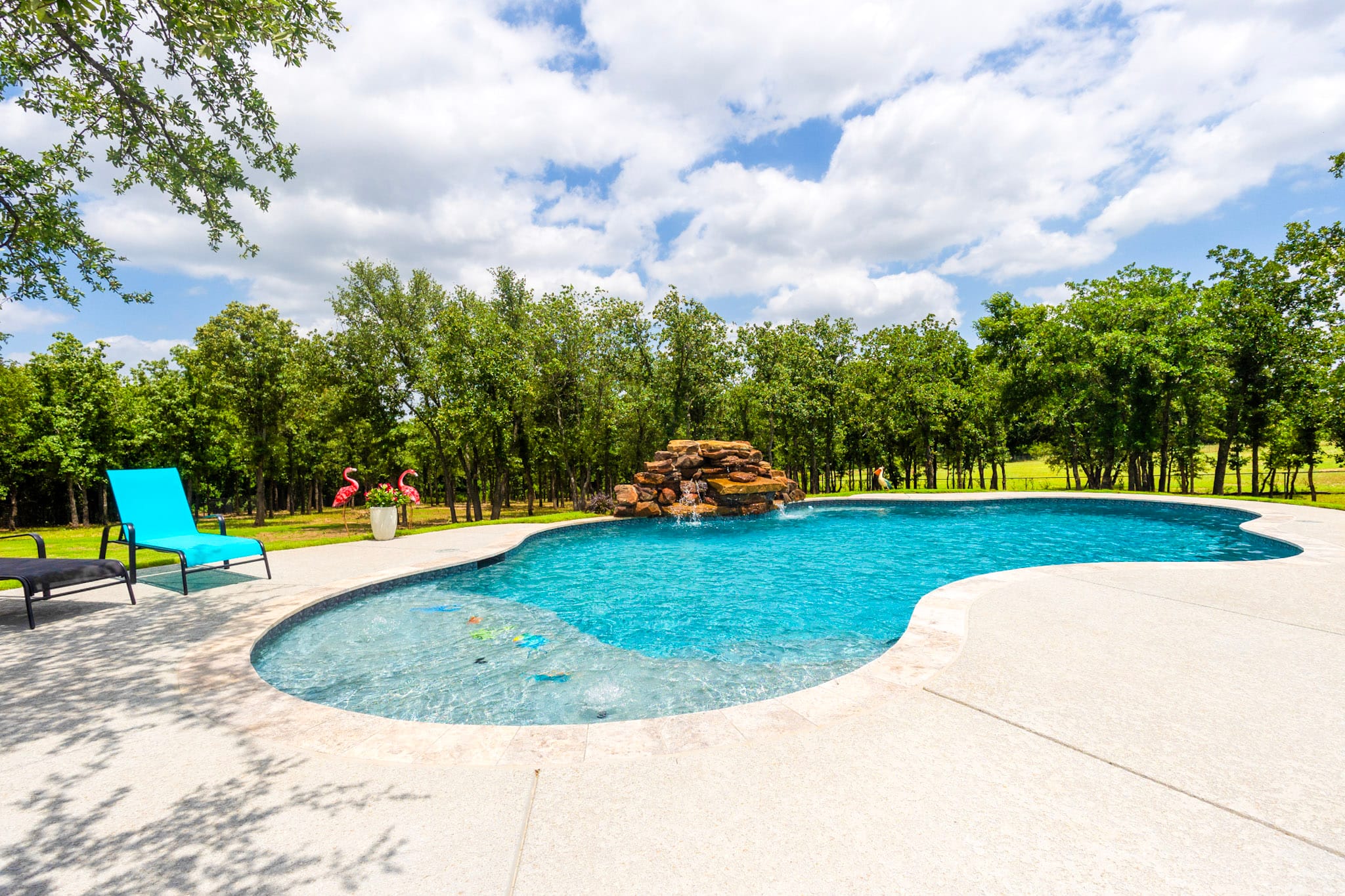 Freeform swimming pool with shallow area and rock waterfall in Weatherford