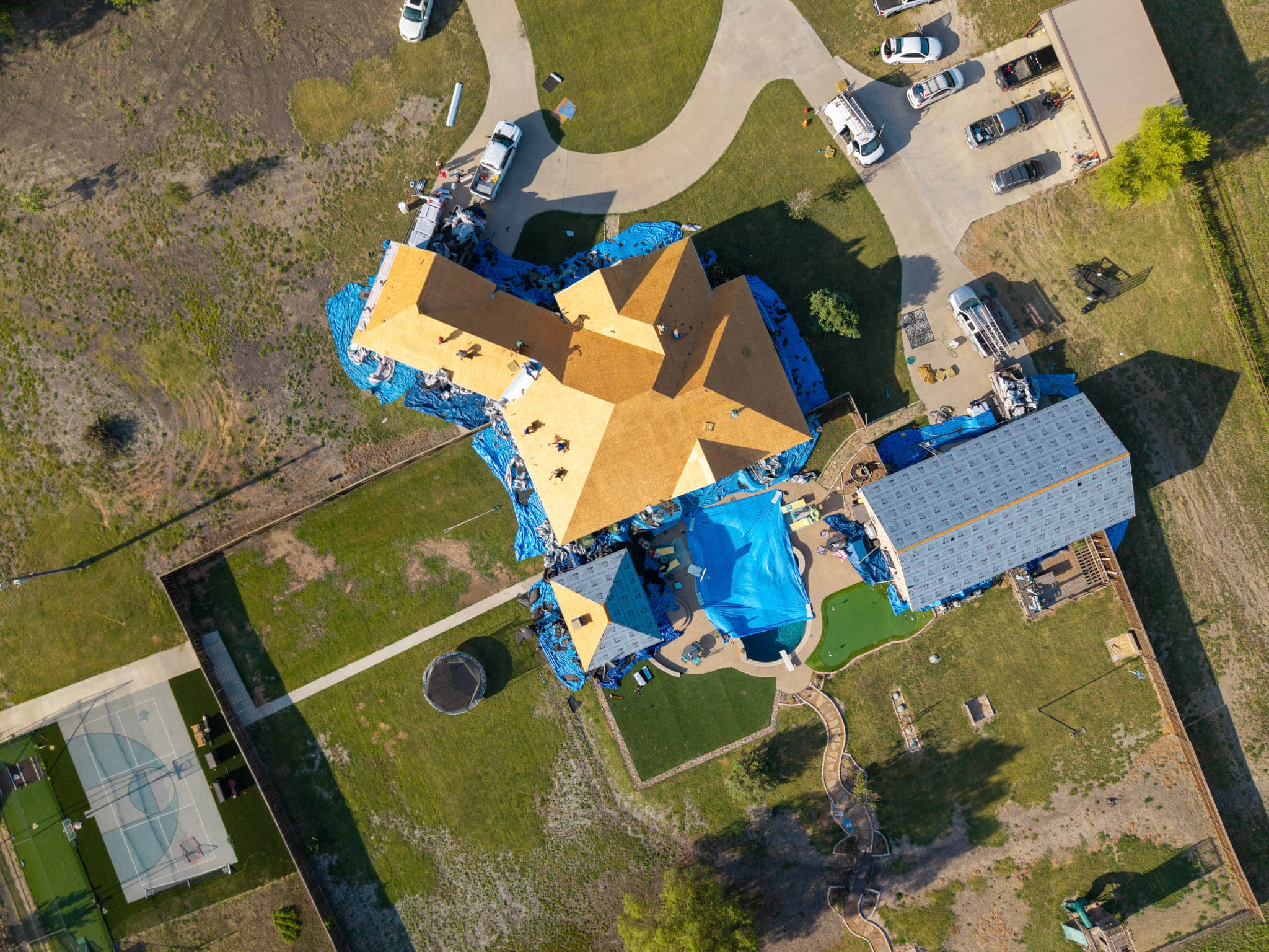 Top-down aerial view of active roofing project on large home in Leonard Texas