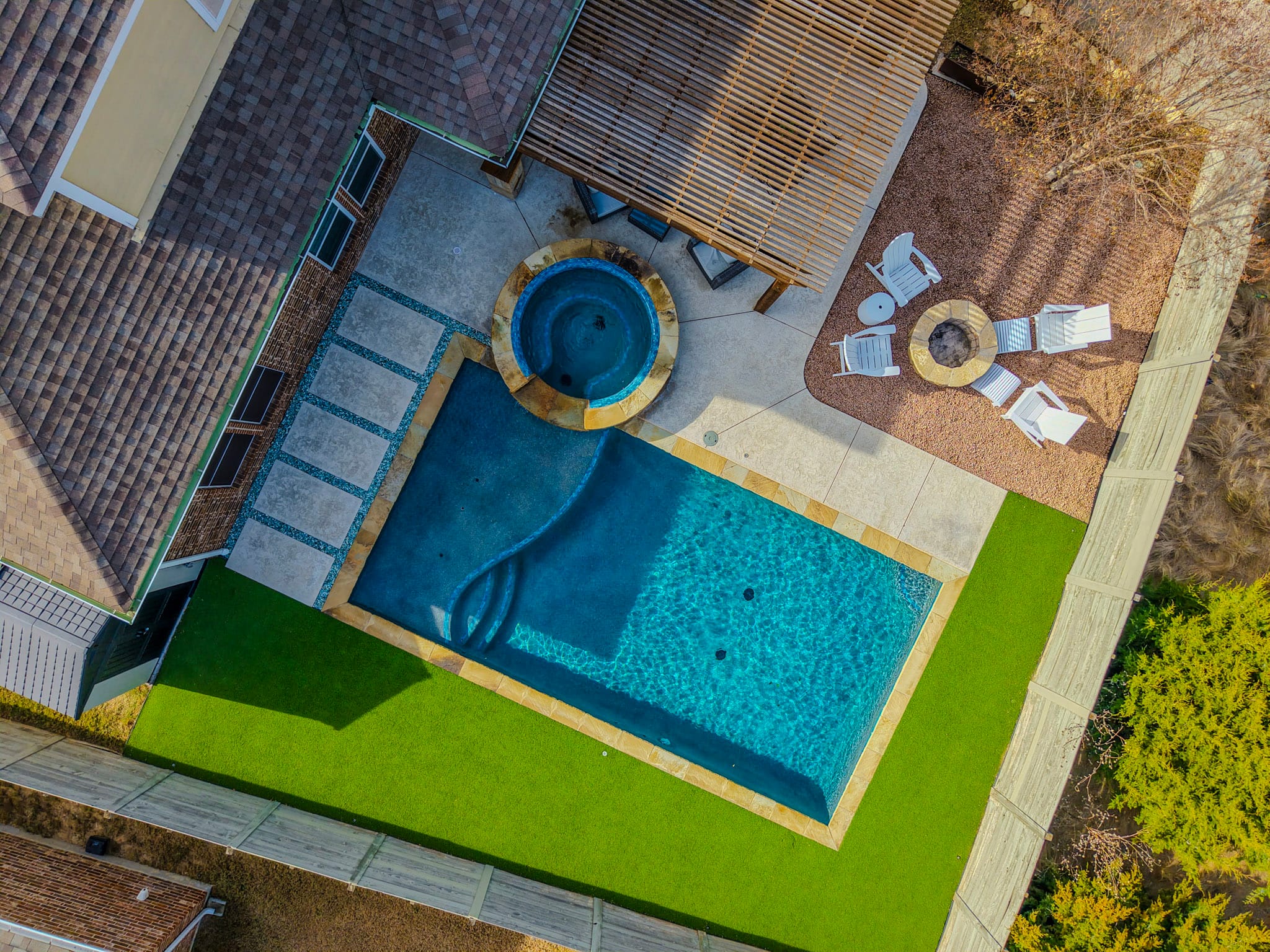 Aerial drone view of pool, raised spa, artificial turf, patio, and fire pit in Northlake Texas