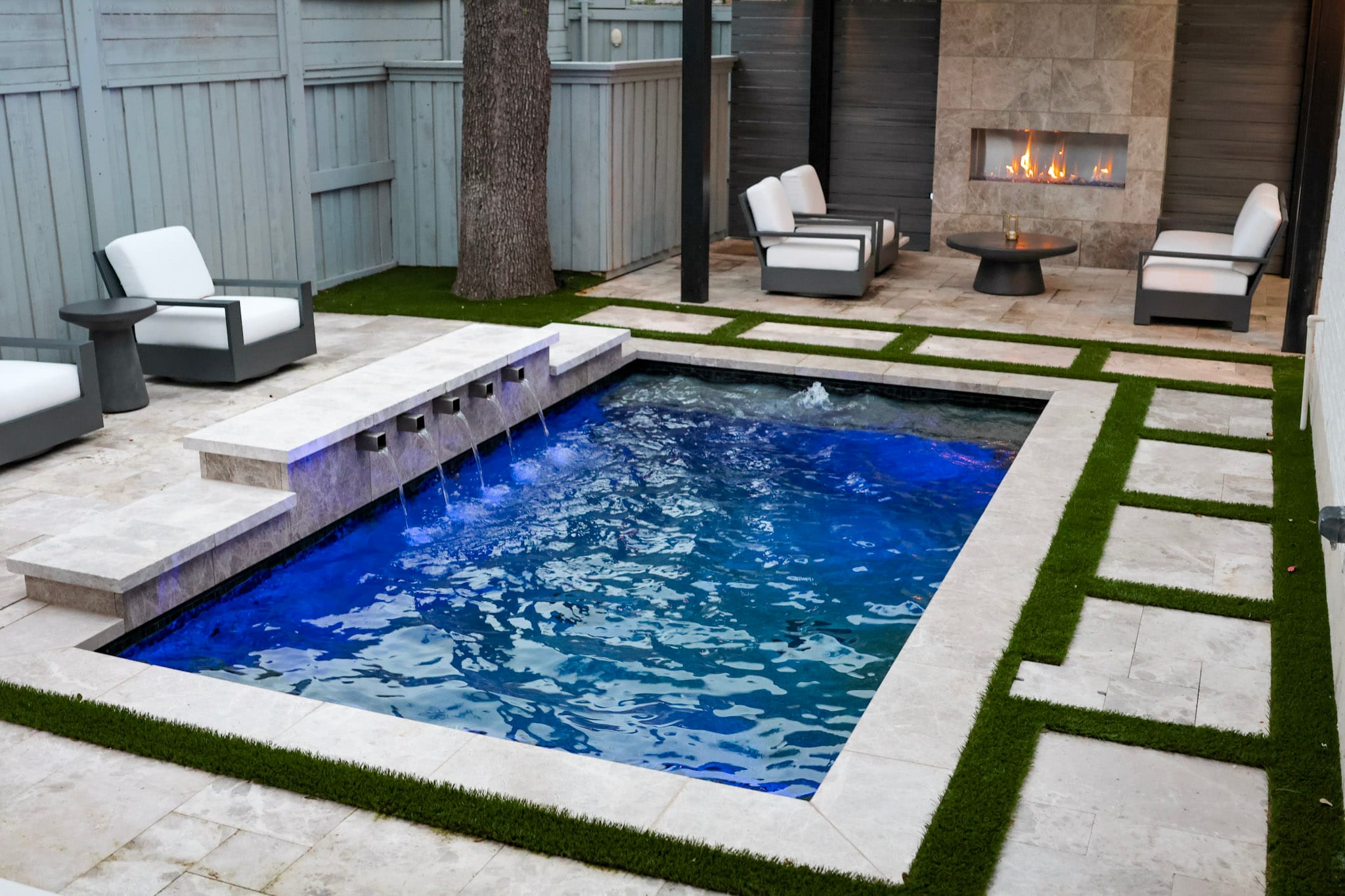 Cocktail pool with water features, turf and covered fireplace area
